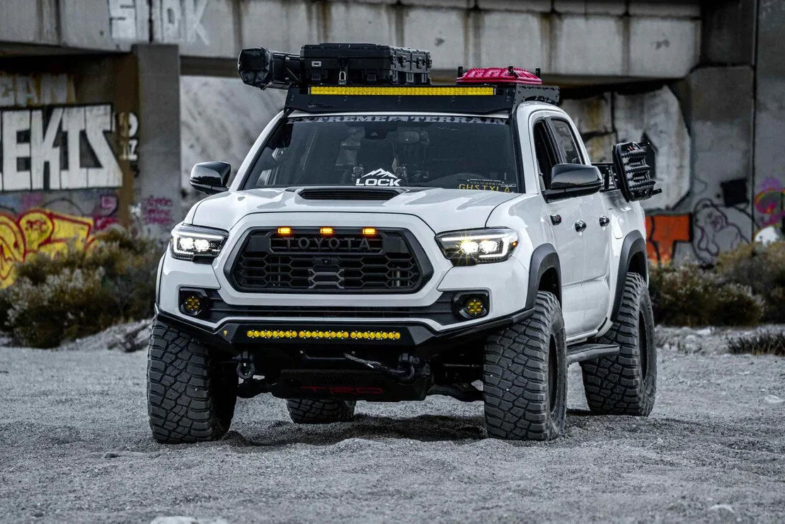 Toyota Tacoma with custom off-road headlights, LED light bar, rooftop rack, and rugged tires