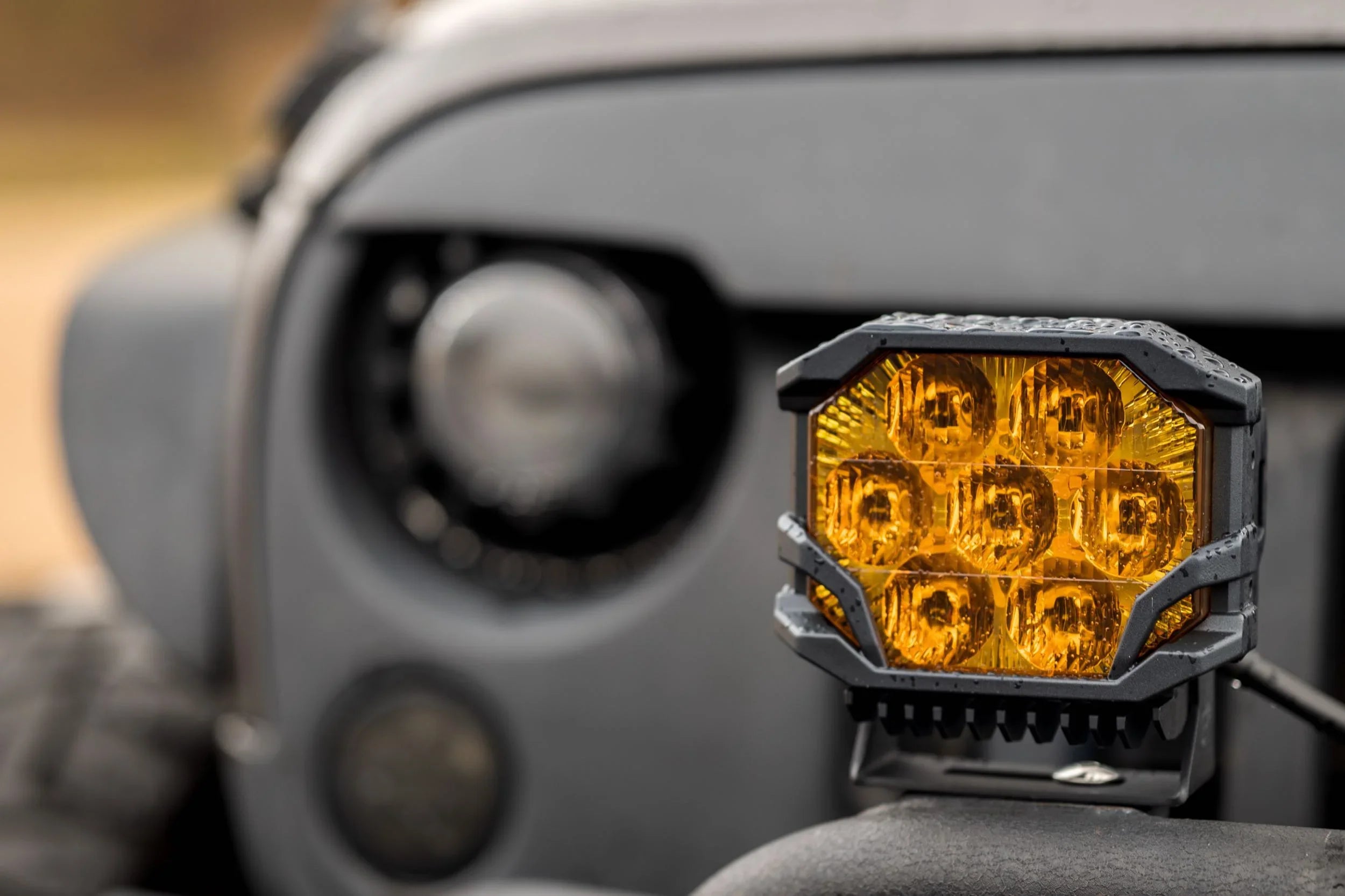Close-up of amber off-road LED pod light mounted on a rugged vehicle bumper