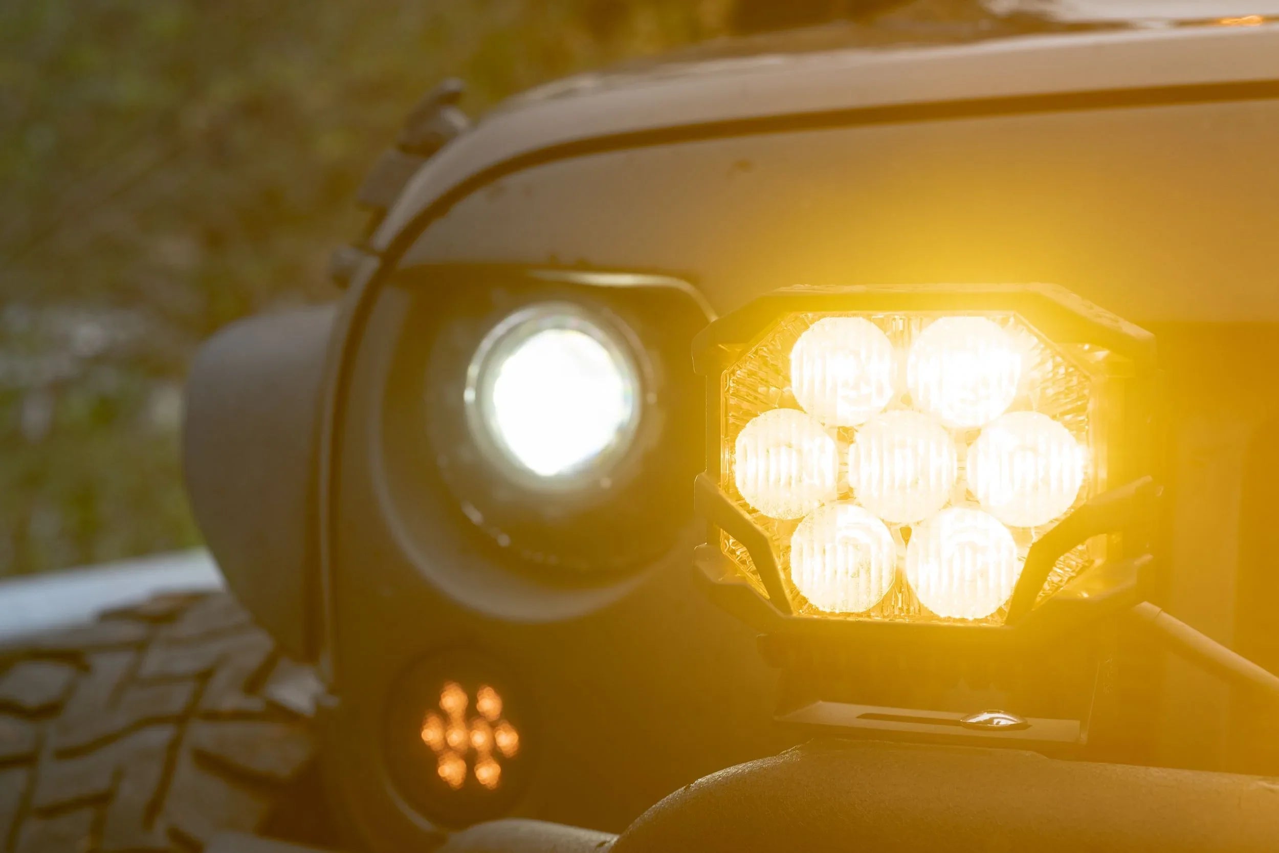 Close-up of off-road LED pod light and vehicle headlight illuminated on rugged truck