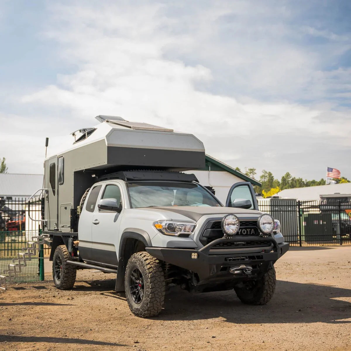 Toyota Tacoma with overland camper and off-road accessories parked outdoors