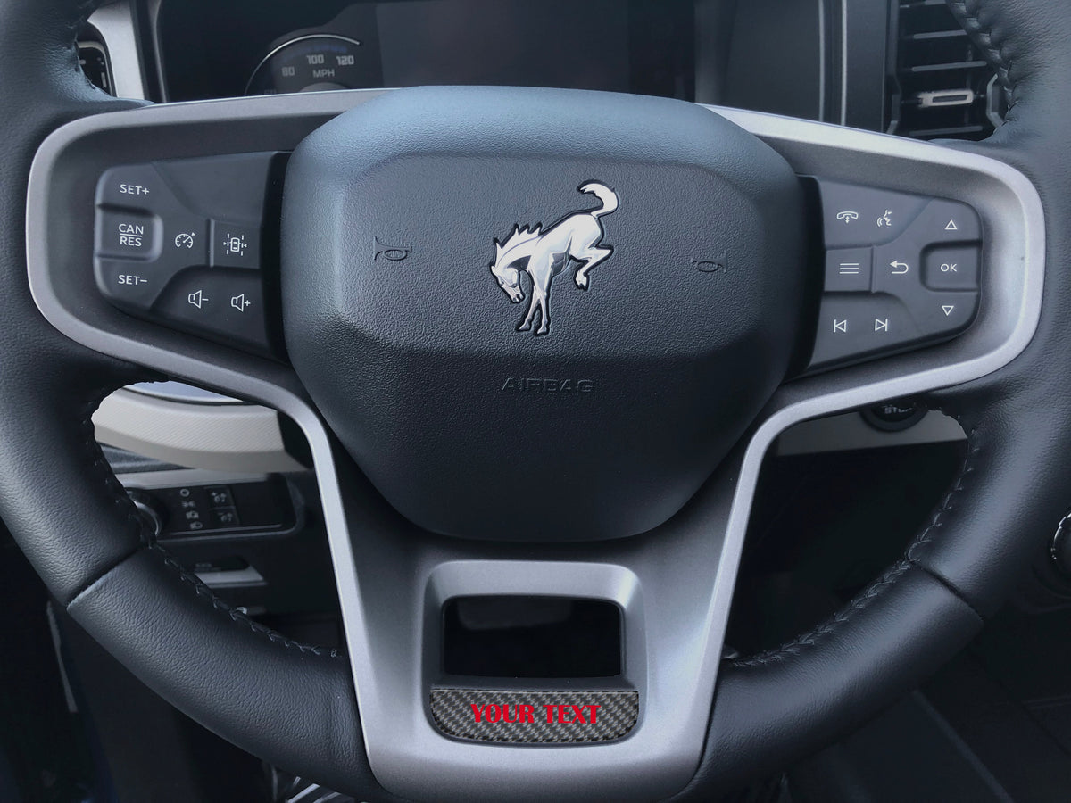 Tufskinz steering wheel accent overlay in red on the lower spoke of a 2021-2026 Ford Bronco steering wheel