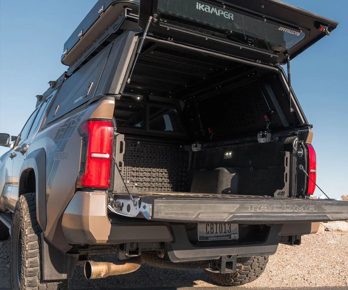 Toyota Tacoma truck bed with overlanding camper shell and storage setup outdoors