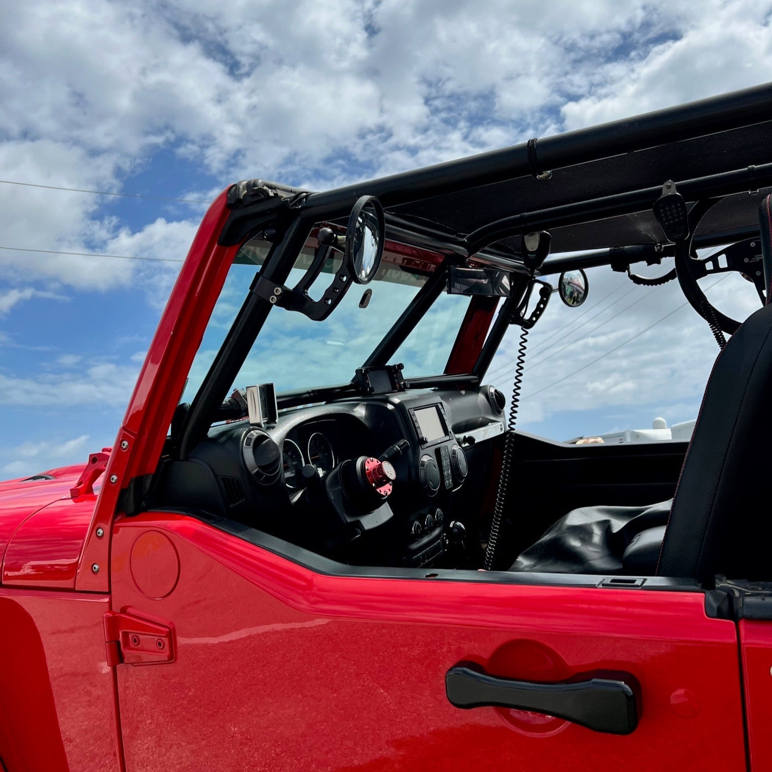 Red off-road vehicle interior with roll cage and adventure gear under blue sky
