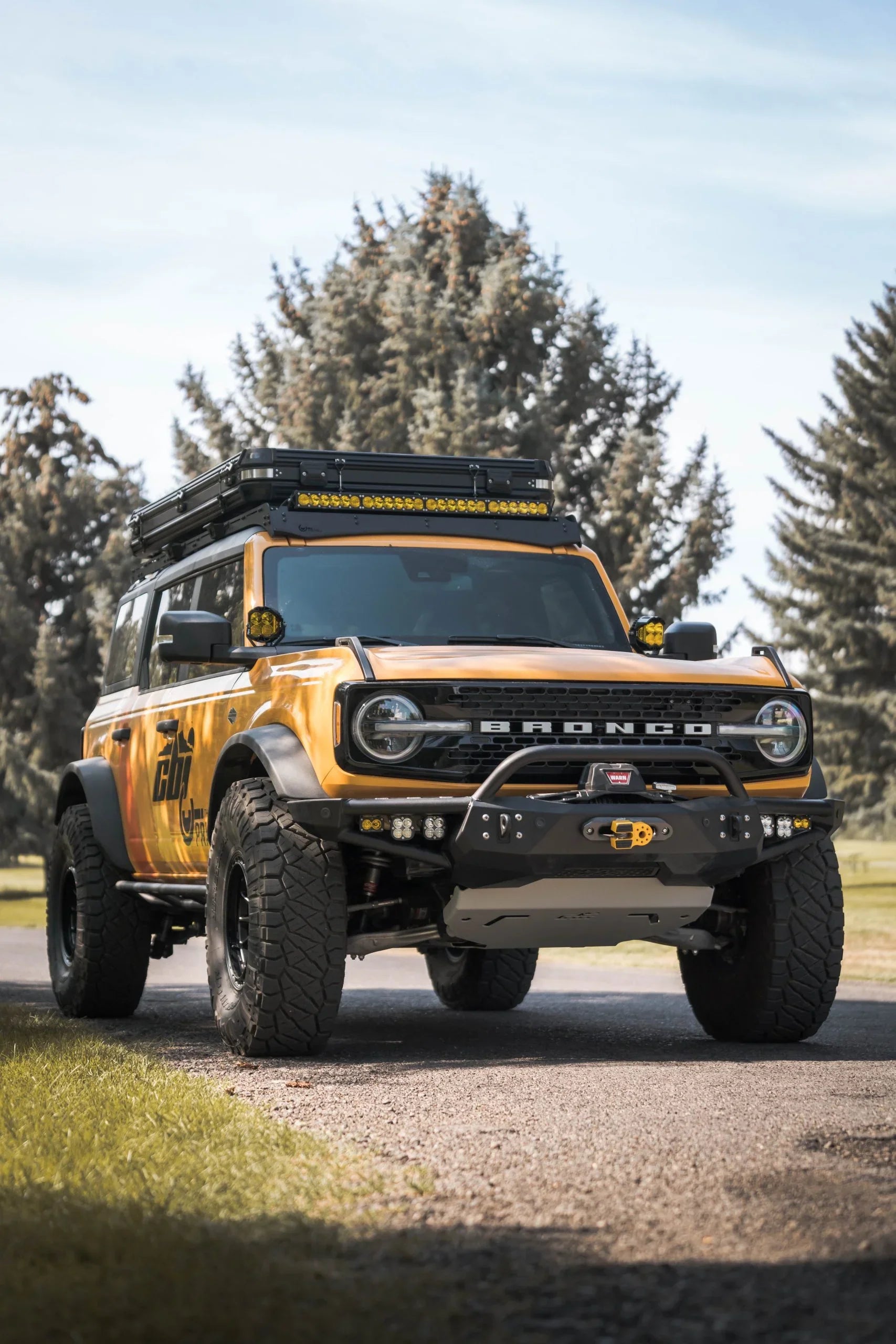 Lifted Ford Bronco with off-road accessories, roof rack, and LED light bar in outdoor setting