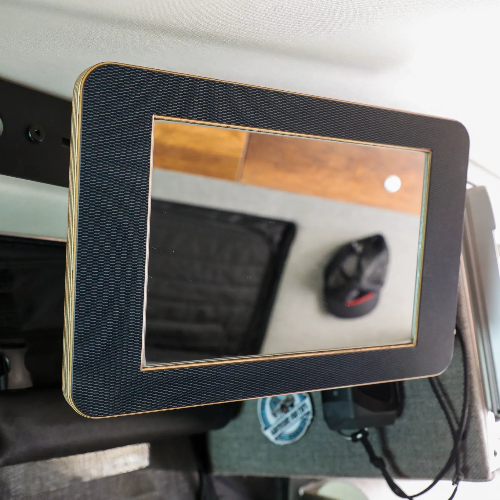 Rectangular vehicle accessory mirror with textured black frame, mounted in overlanding setup