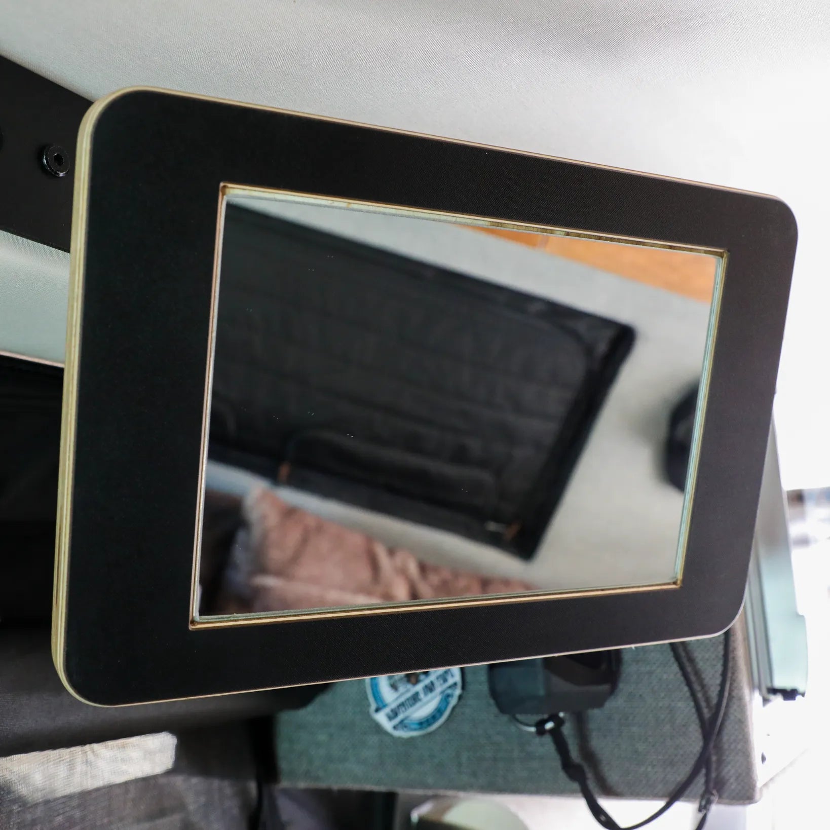 Rectangular black-framed track mirror mounted inside a vehicle for overlanding use