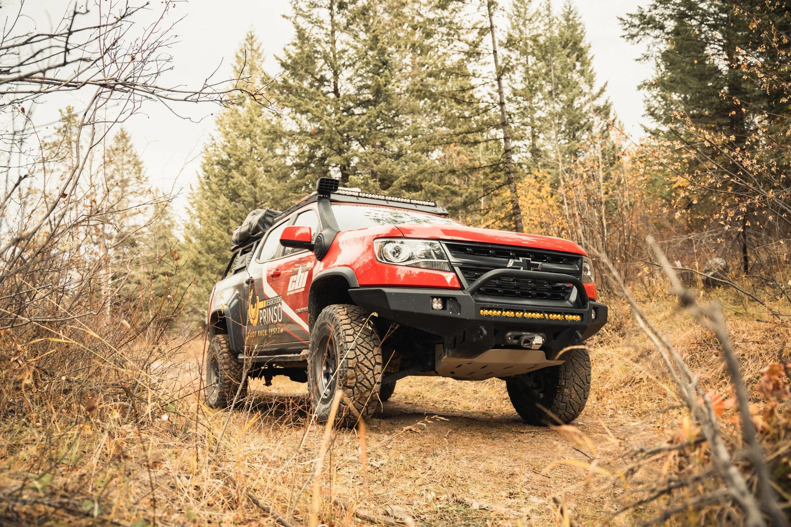 Chevy Colorado overland truck with bed rack and off-road gear on forest trail