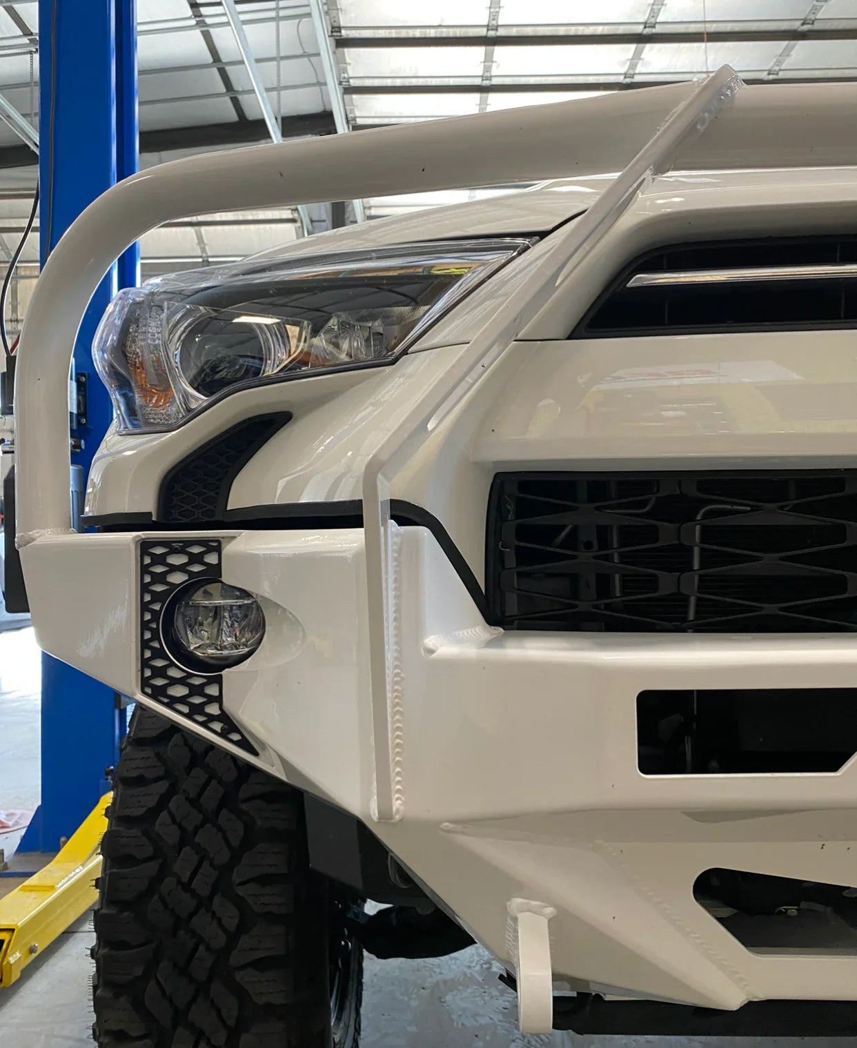 White Toyota 4Runner with off-road adventure front bumper and grille guard in a garage