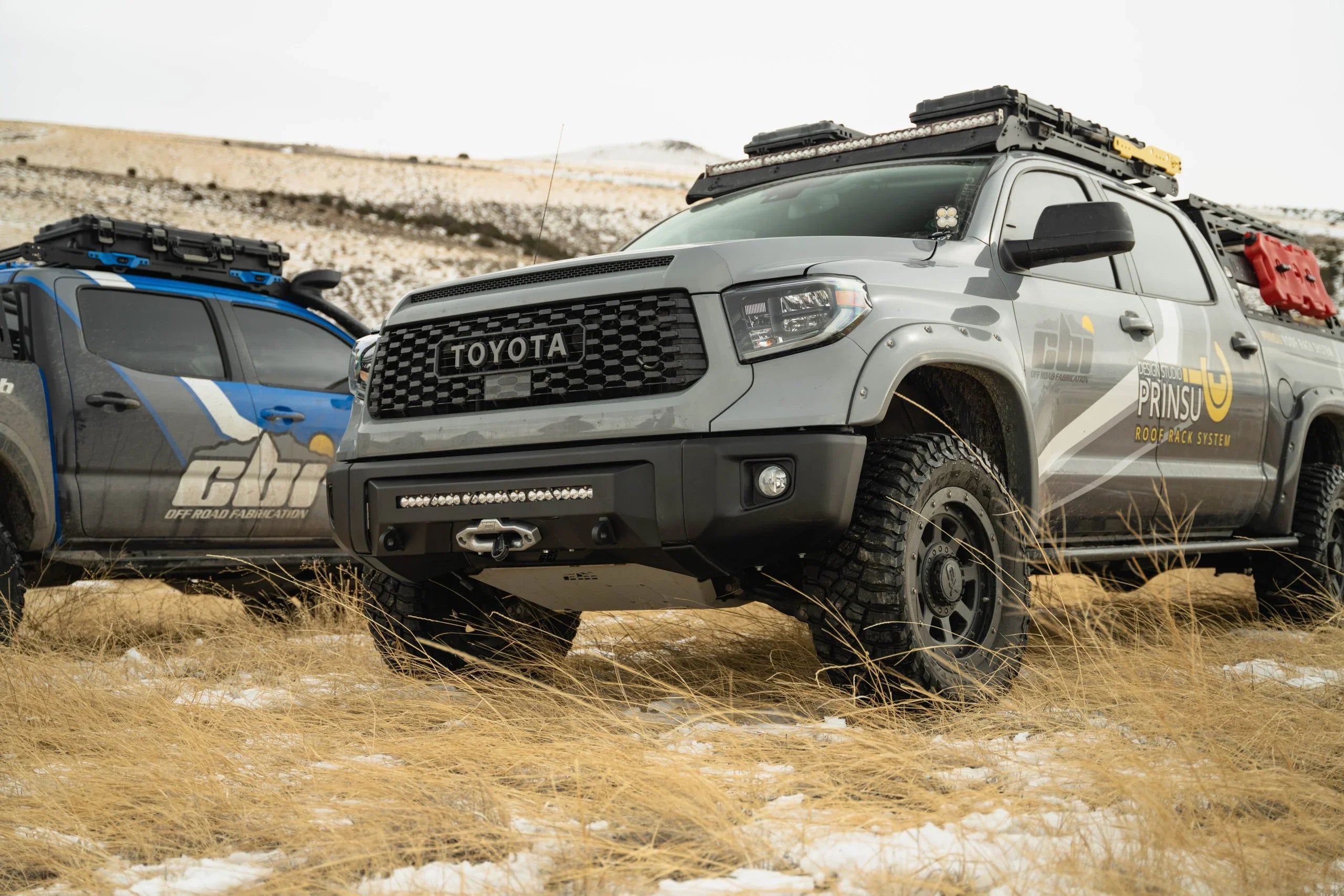 Toyota Tundra with covert front bumper and off-road accessories in a snowy, grassy field