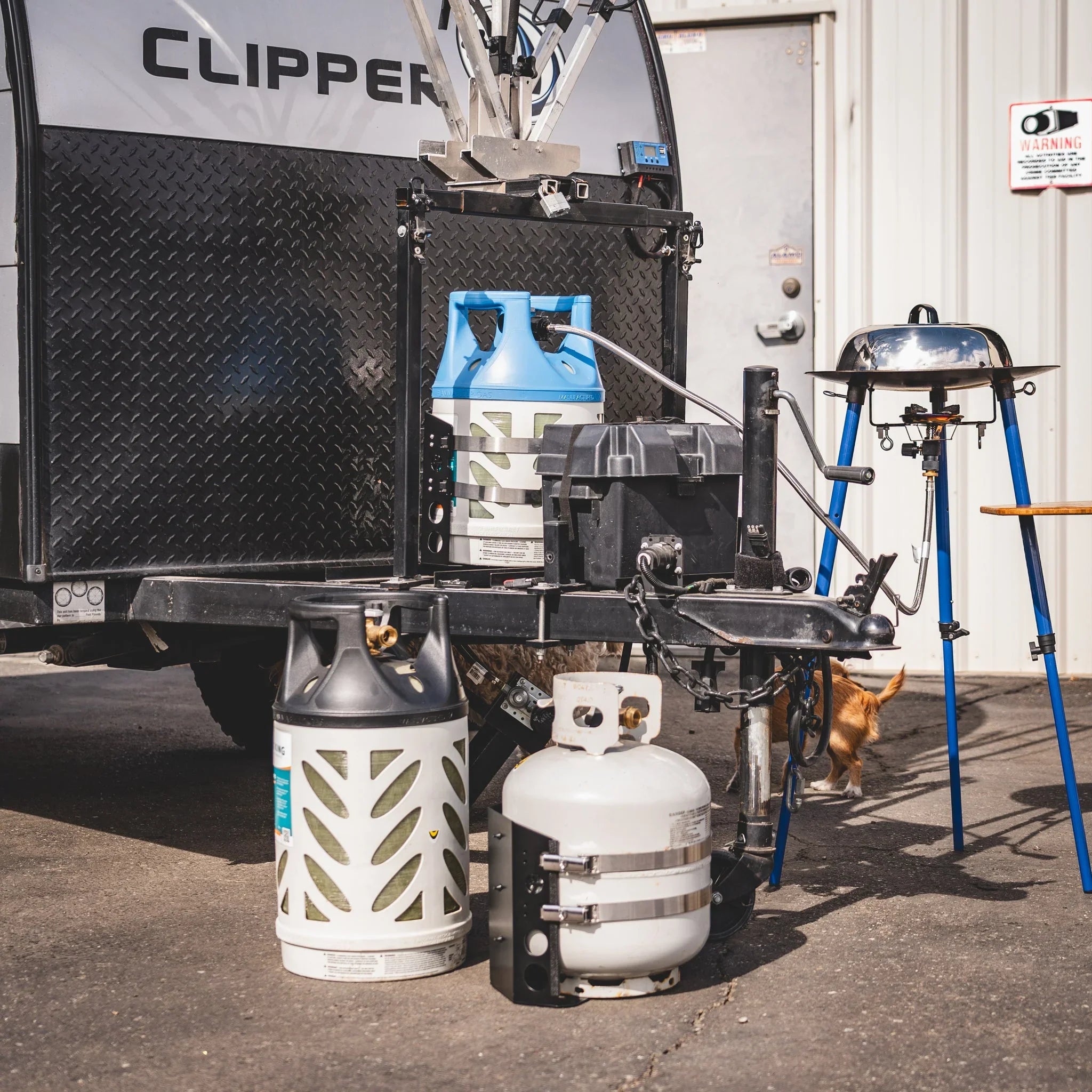 Propane tanks and portable grill setup at camper trailer for overlanding or camping