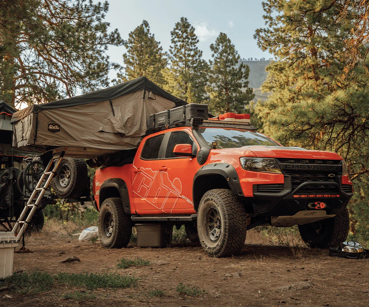 Chevy Colorado overlanding truck with Prinsu rack, rooftop tent, and camping gear in forest