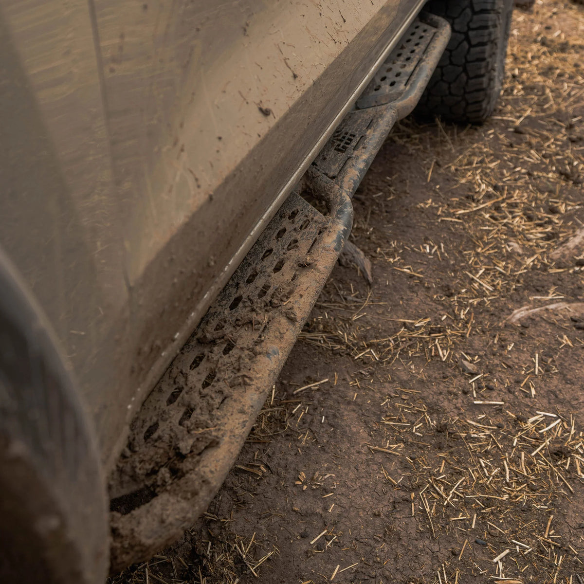 Muddy off-road vehicle with rugged side step rock slider in dirt terrain