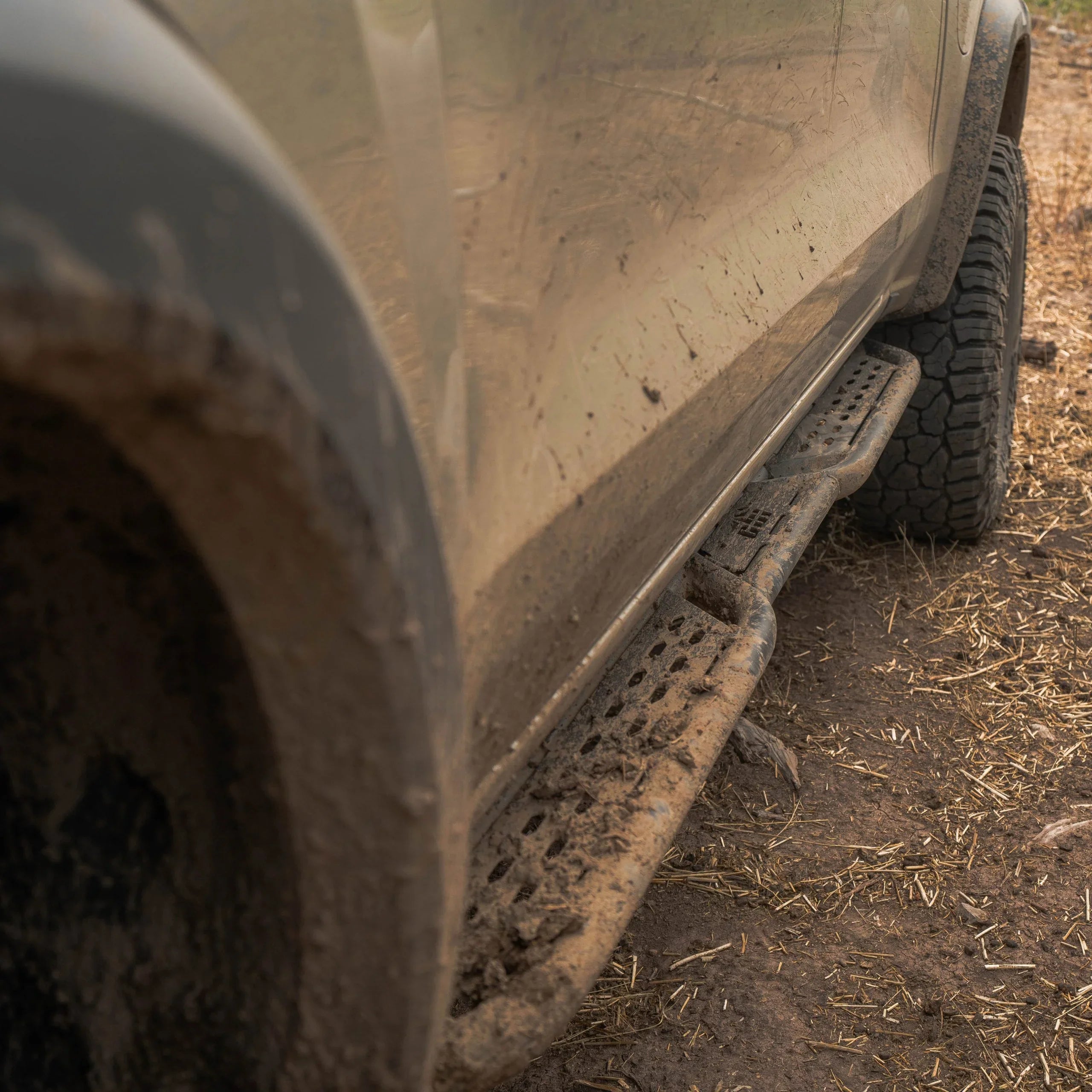 Muddy off-road vehicle with rugged side step on dirt trail, showcasing overlanding gear.