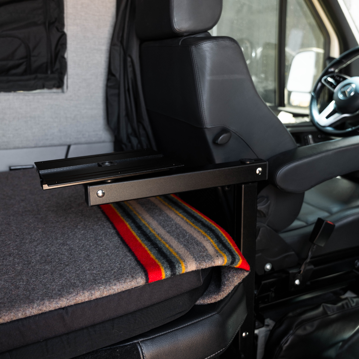 Overland vehicle interior with fold-out metal table, blanket, and black leather seats