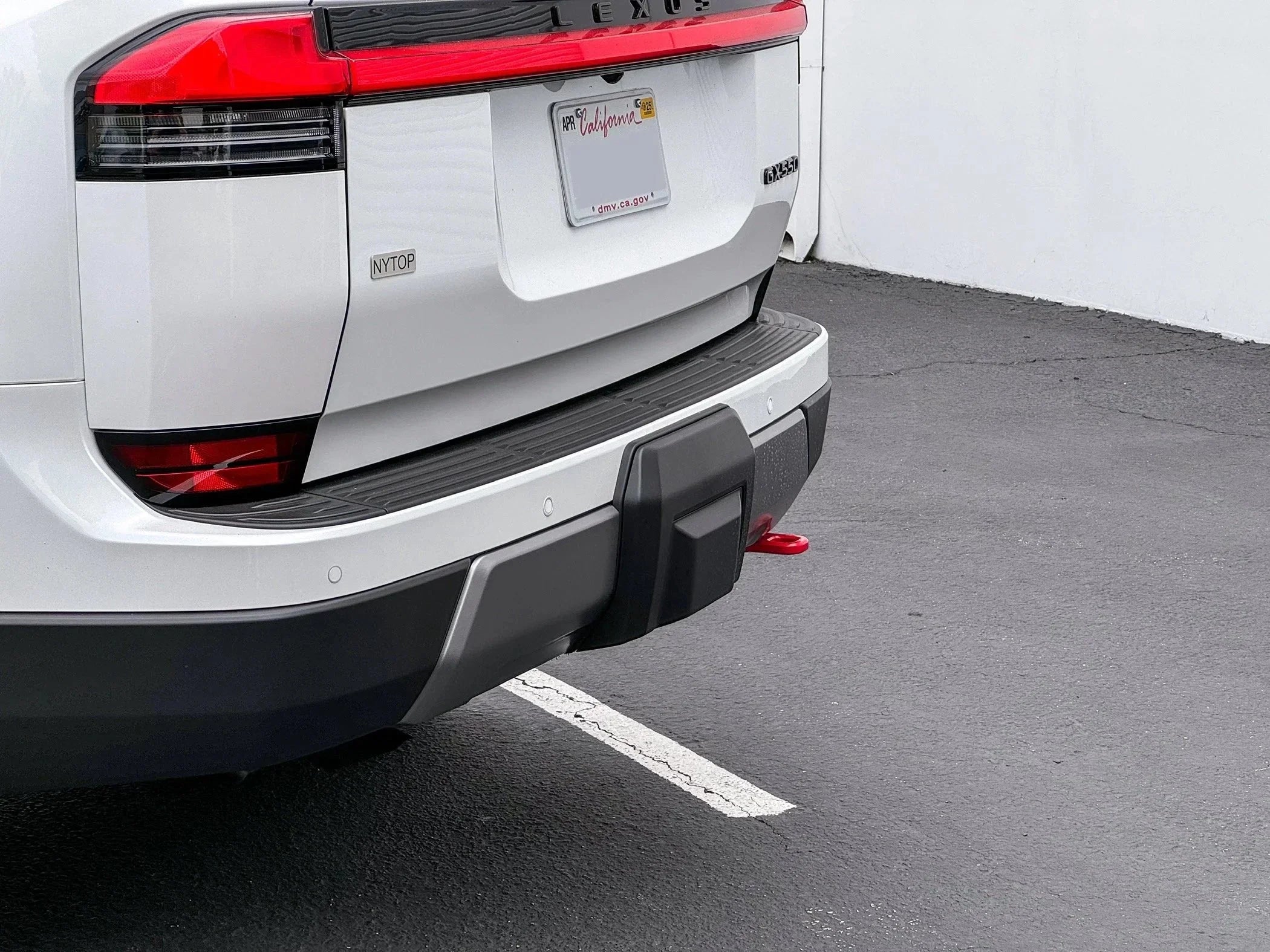White SUV rear bumper with red tow hook in parking lot