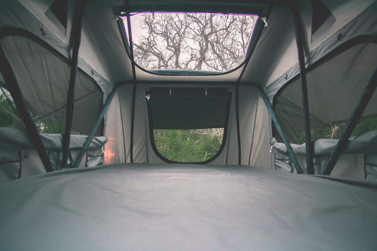 ROAM Vagabond rooftop tent interior with a gray mattress sheet in the foreground and a skylight window overhead