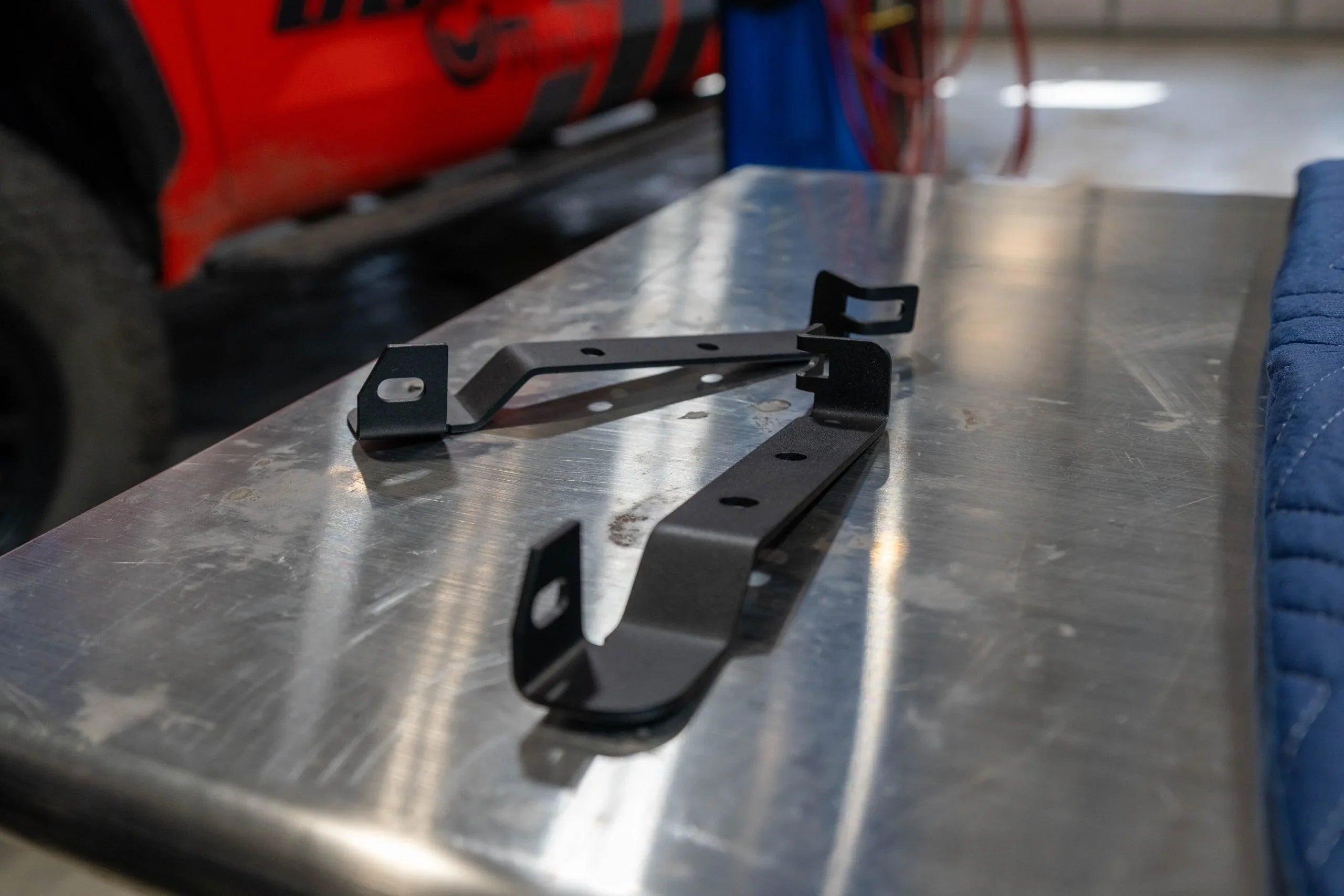Black steel mounting brackets for off-road vehicle accessories on metal workbench