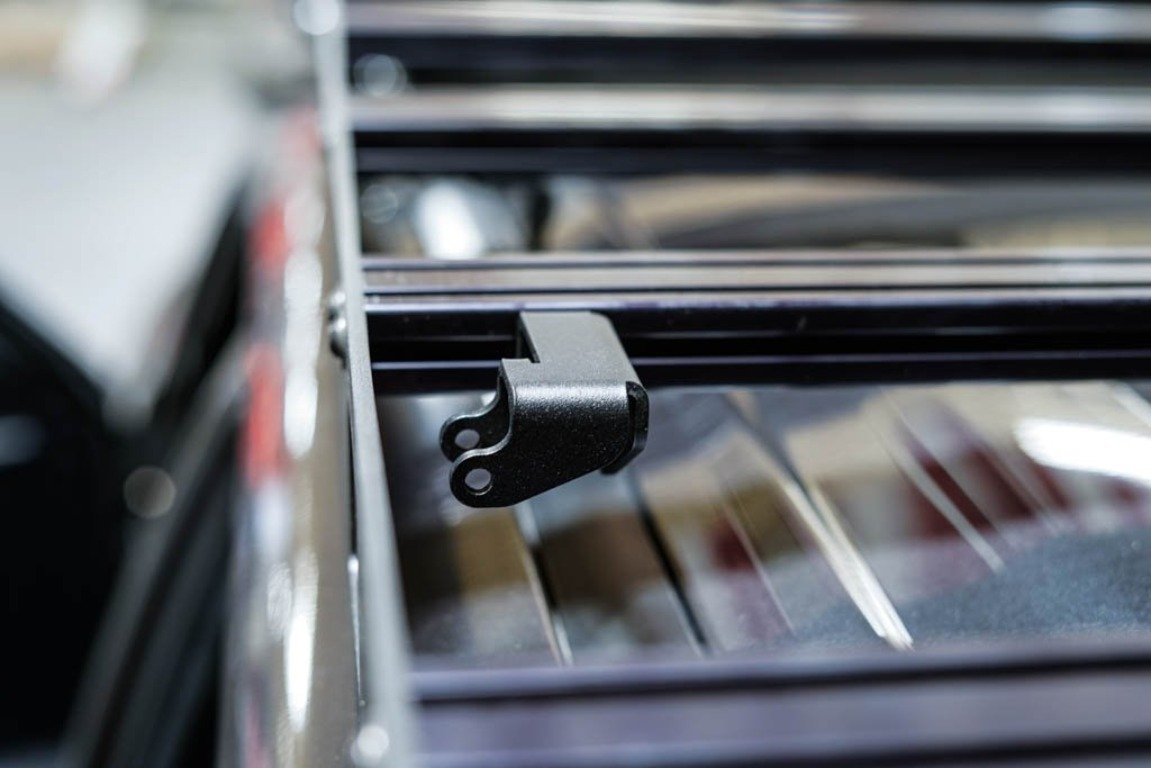 Close-up of a black roof rack mounting bracket on a vehicle, ideal for overlanding gear.