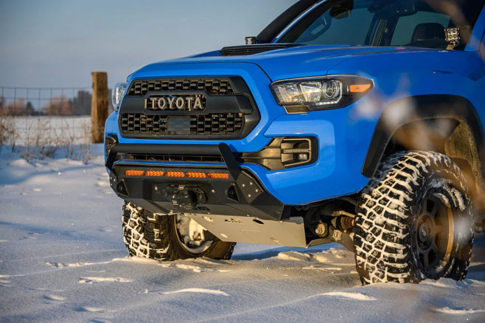 Blue Toyota Tacoma with off-road bumper and lights in snowy landscape