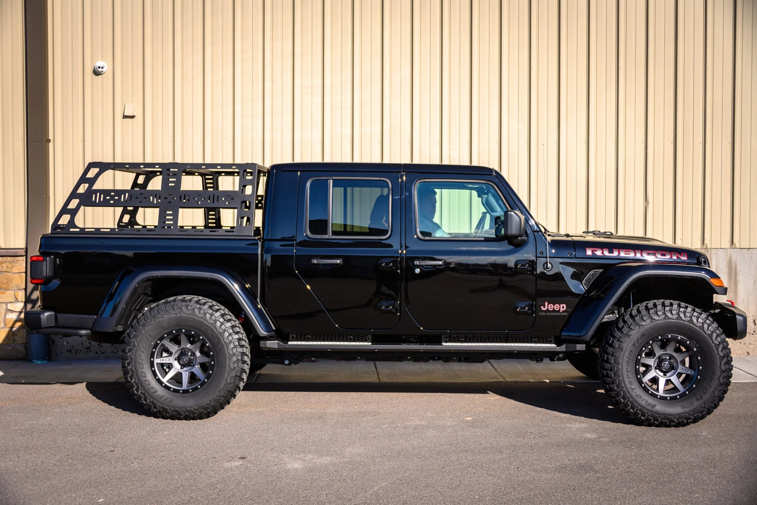 Black Jeep Gladiator Rubicon with off-road tires and modular bed rack parked outdoors