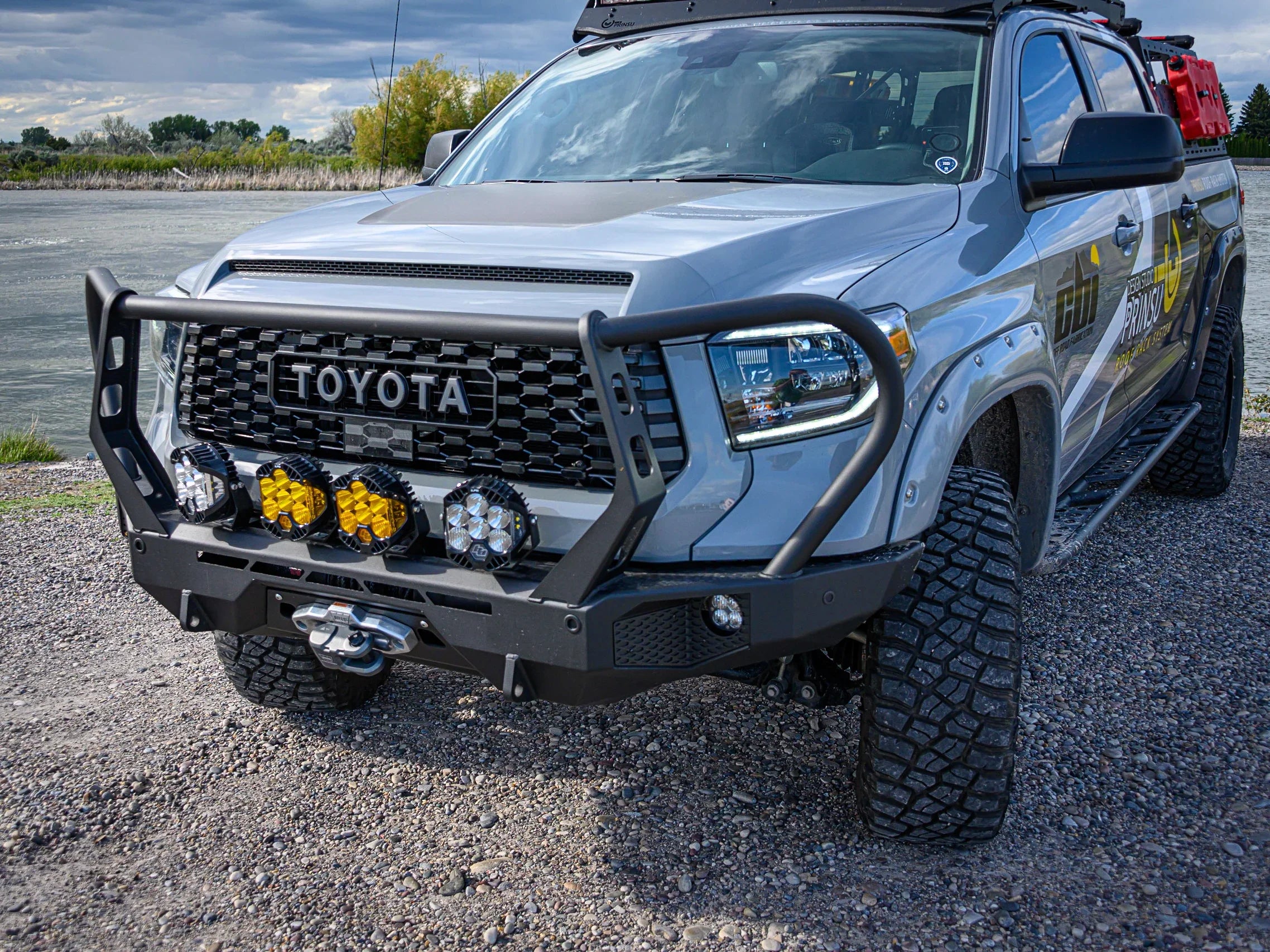 Toyota Tundra outfitted with off-road bumper, LED lights, and overlanding gear by a river