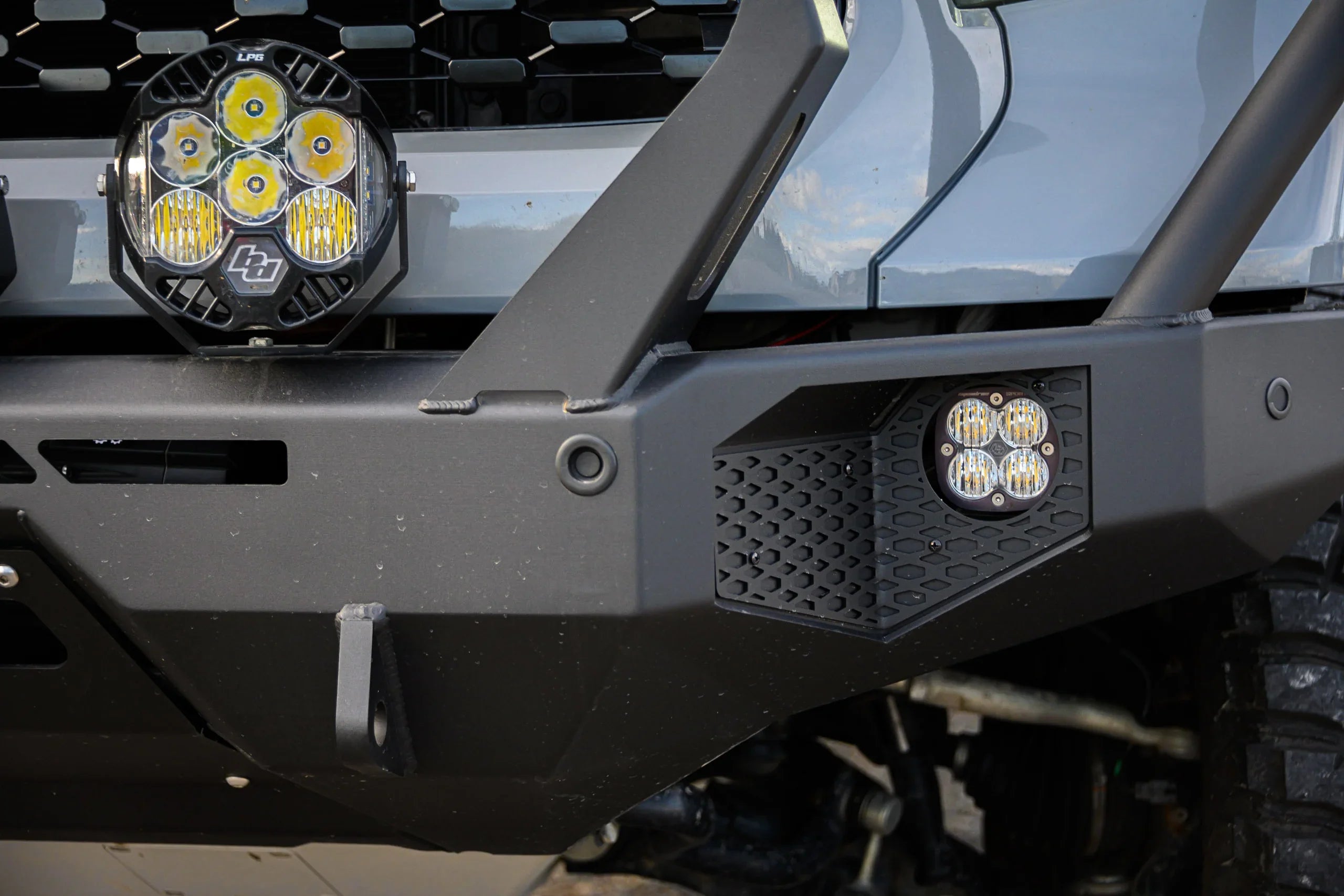 Close-up of off-road vehicle aftermarket steel bumper with LED pod and round driving lights