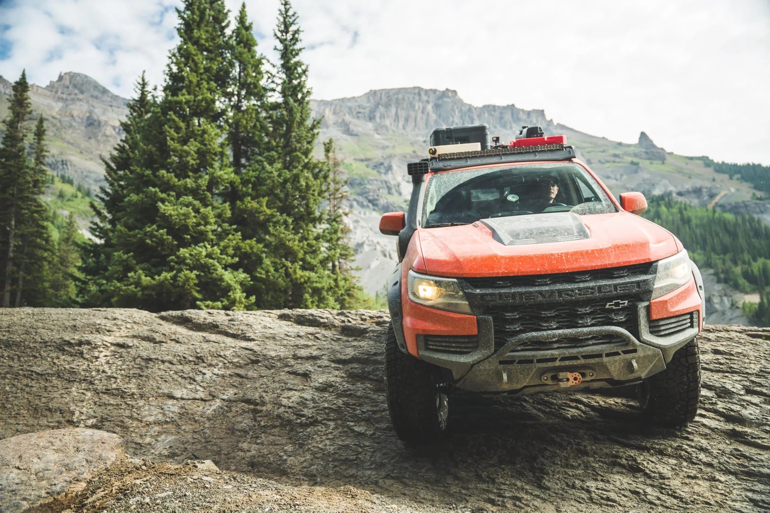 Overlanding Chevy Colorado truck with camping gear off-road in mountain wilderness