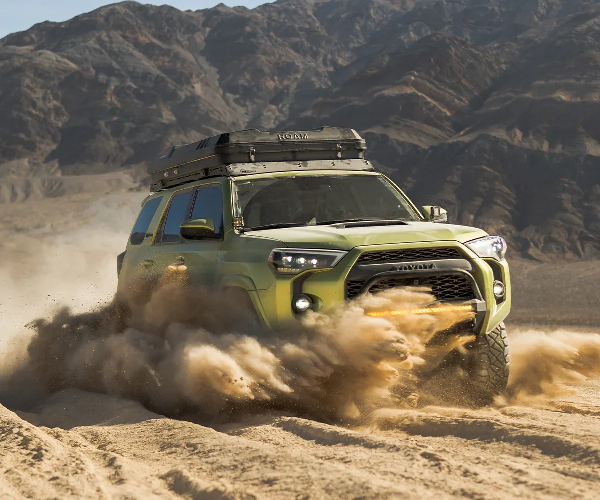 Toyota 4Runner off-road with rooftop tent kicking up sand in Death Valley desert