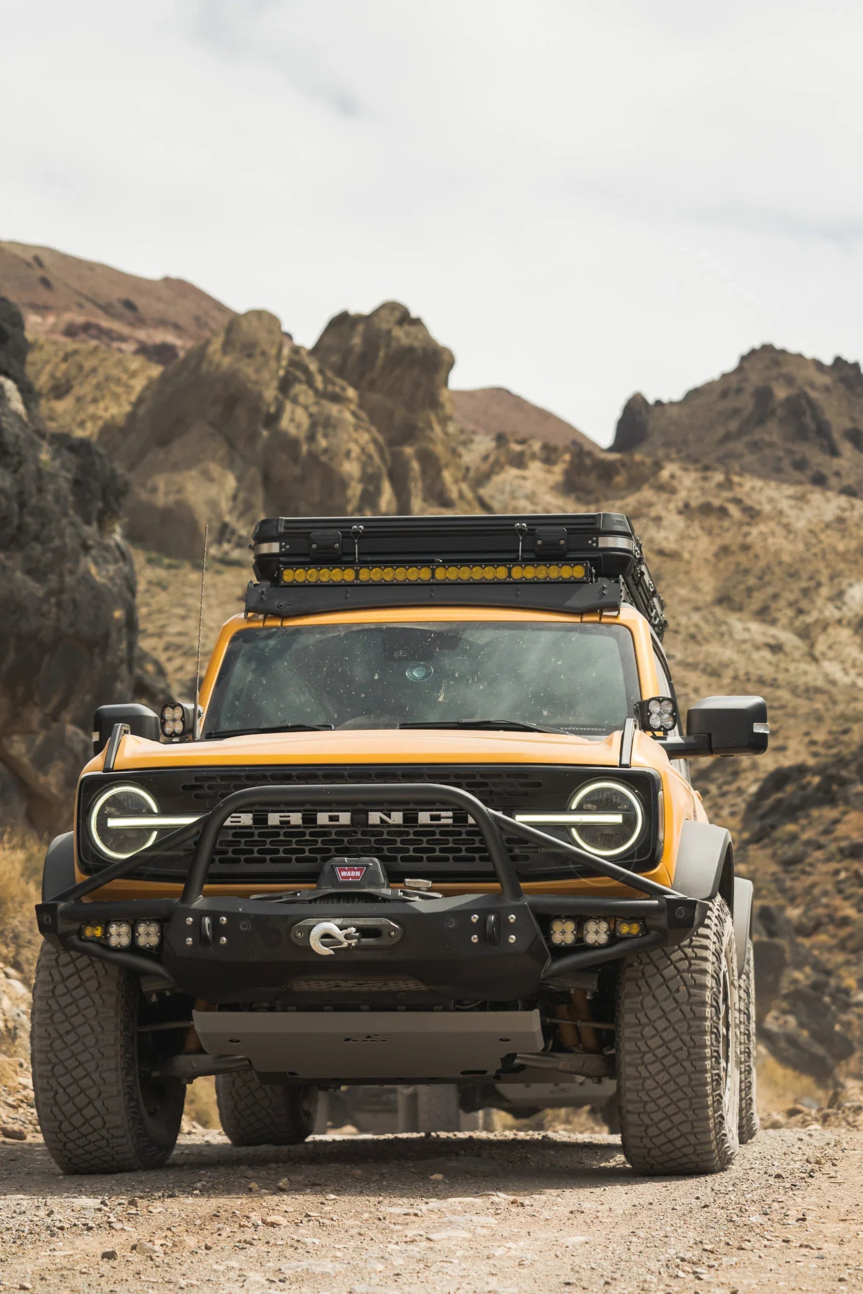 Yellow Ford Bronco with off-road accessories on a rocky desert trail