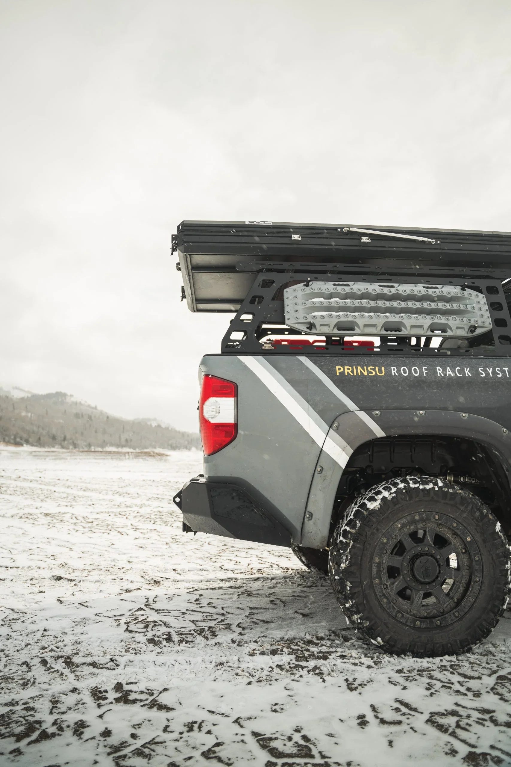Overland truck with Prinsu roof rack and gear, off-road in snowy landscape