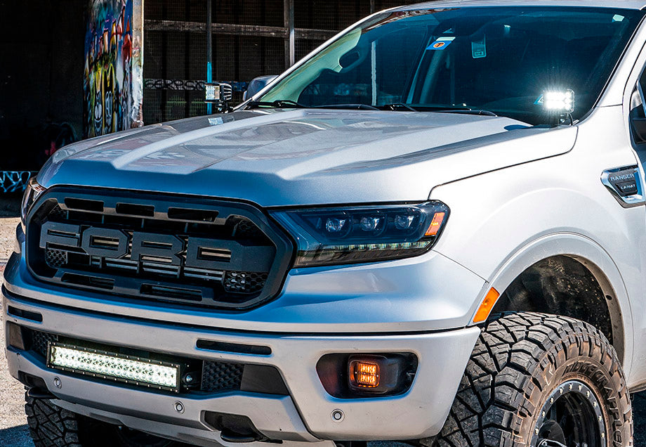 Silver Ford Ranger truck with off-road tires and LED light bar parked outdoors