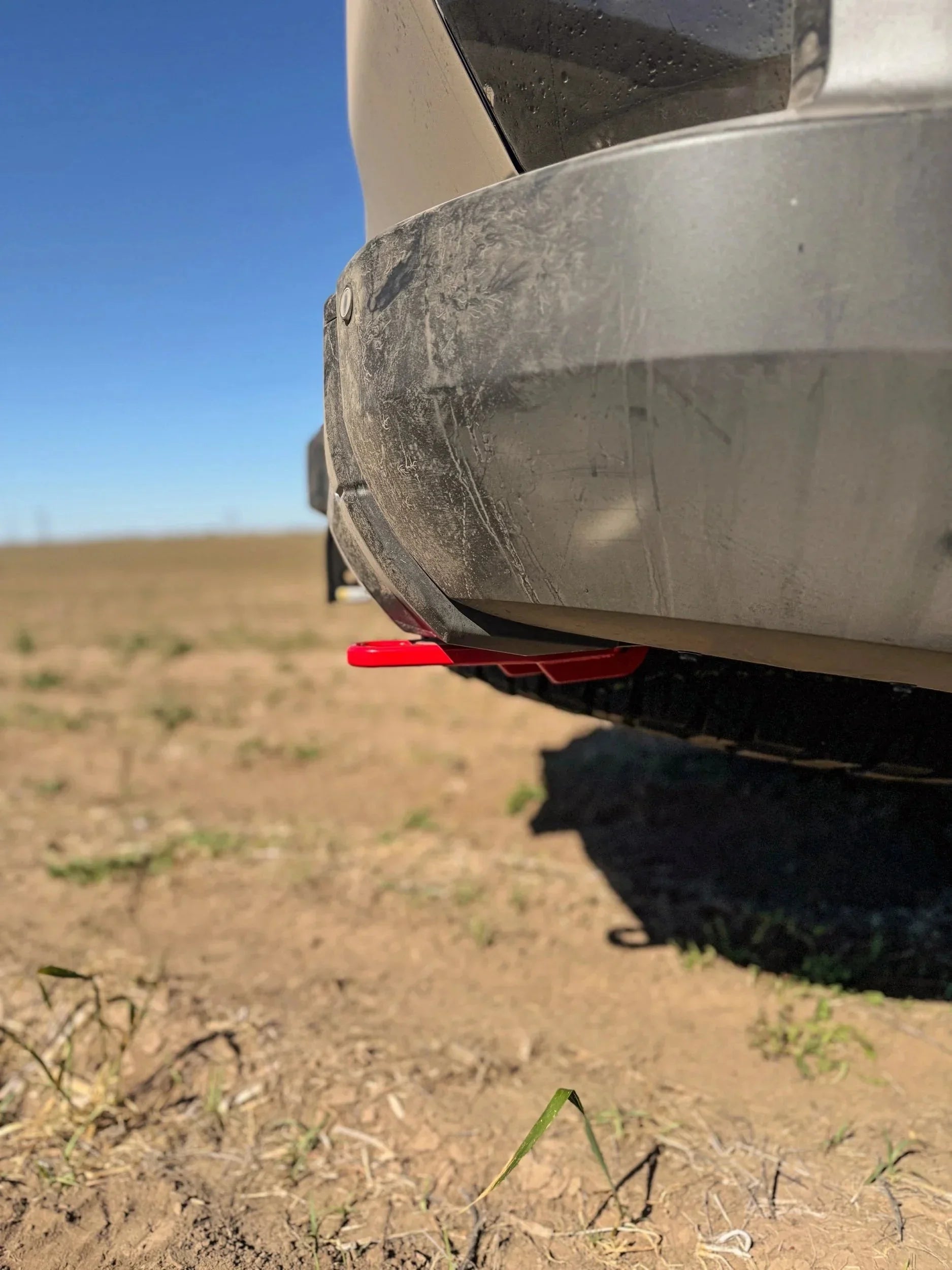 Close-up of off-road vehicle rear bumper with red recovery point on dirt trail