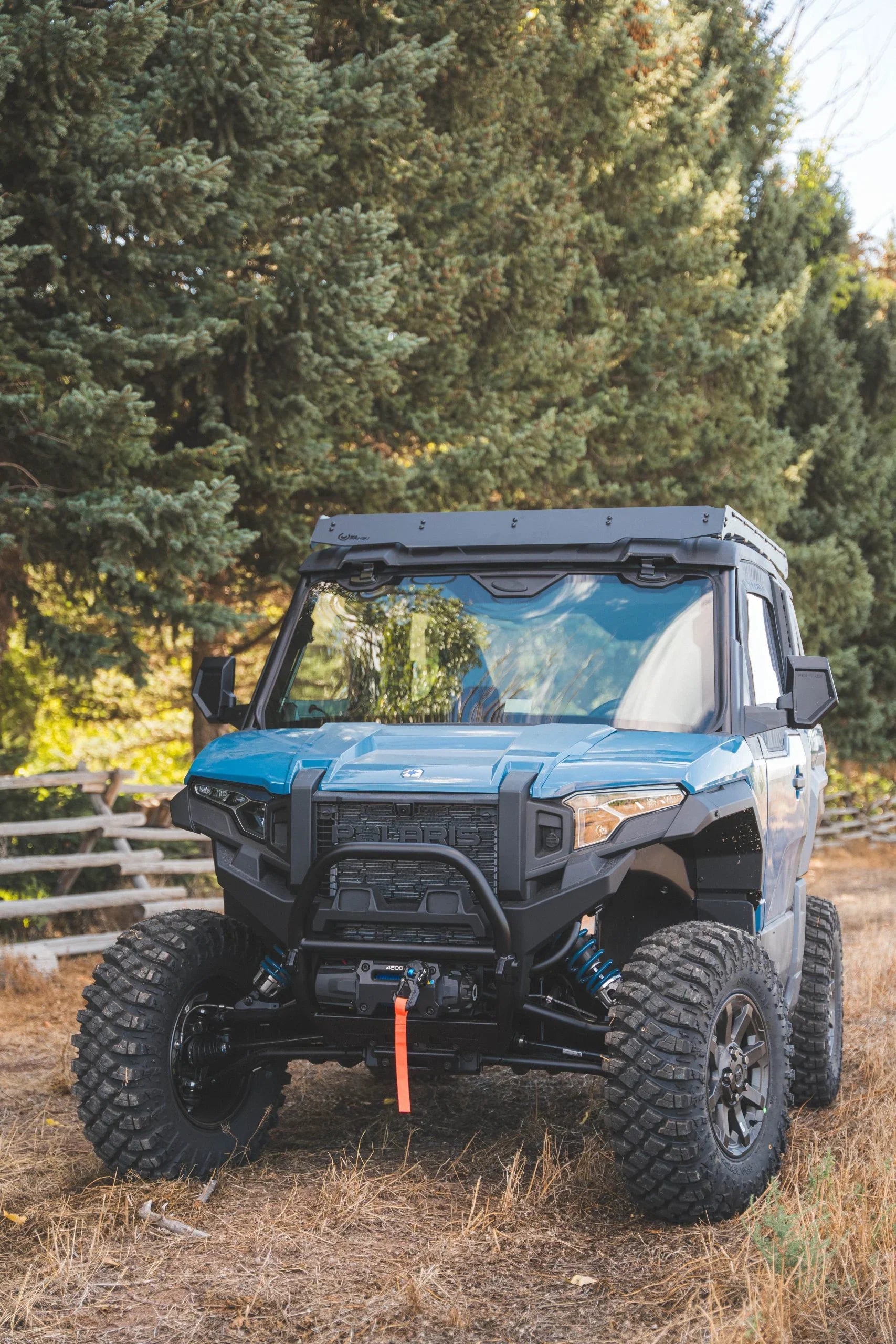 Off-road utility vehicle with rugged tires and front winch parked outdoors in a forest setting