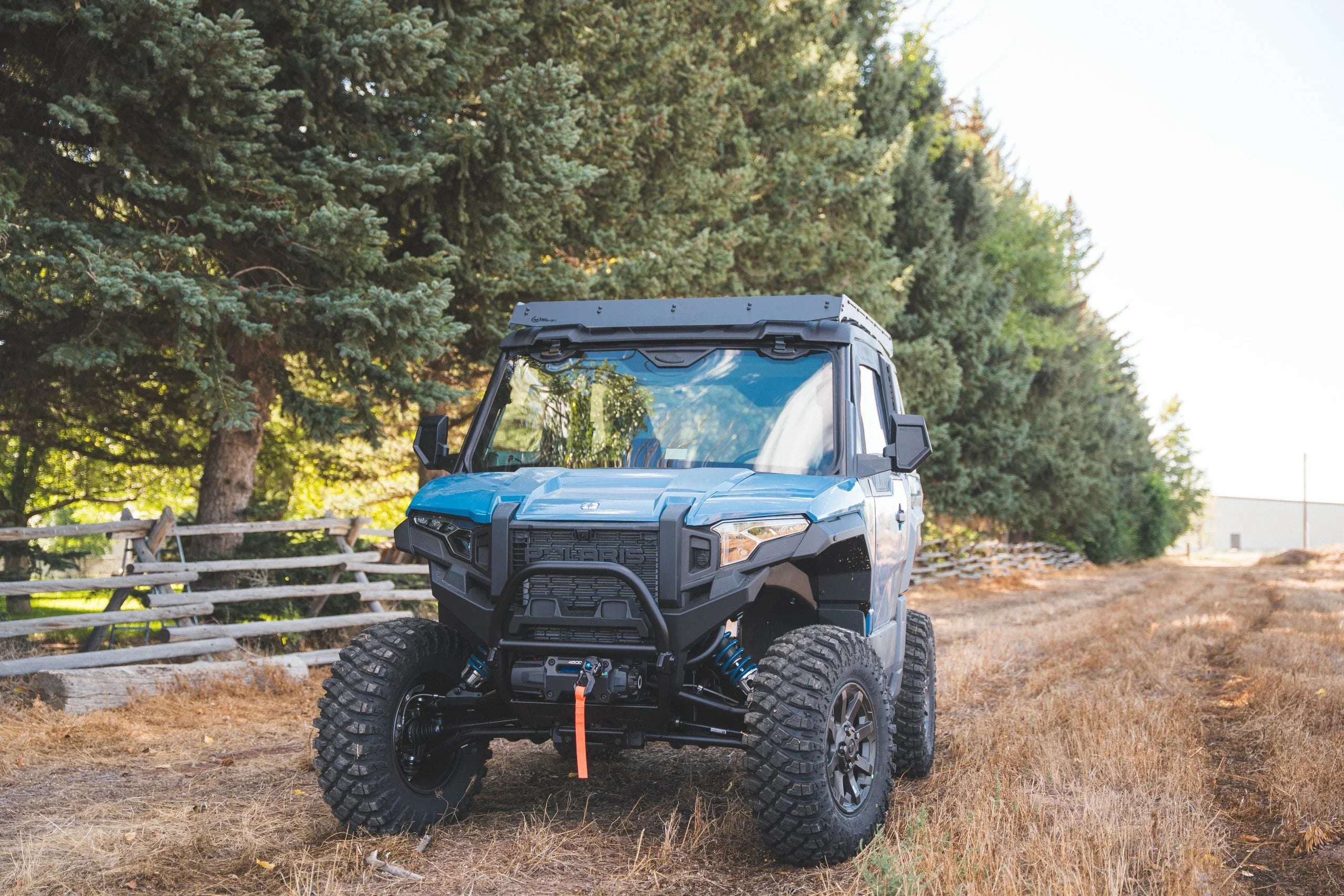 Off-road expedition utility vehicle with rugged tires parked on a dirt trail near trees