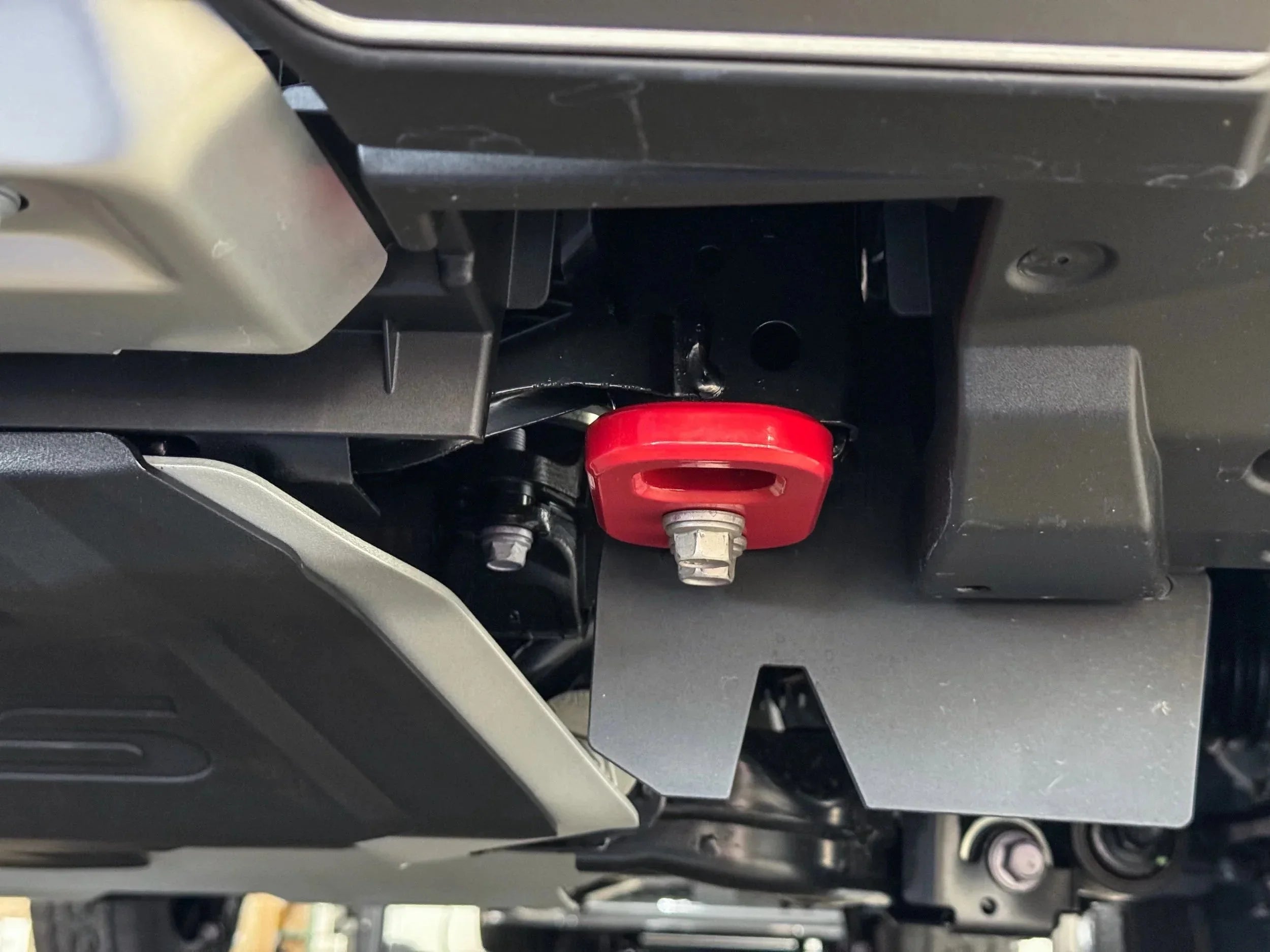 Close-up of red recovery point on vehicle undercarriage with skid plate for off-road use