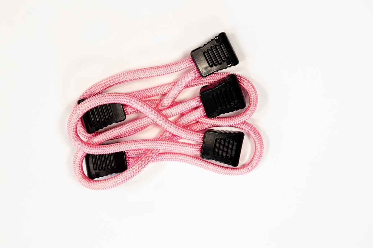 Pink bungee cords with black plastic hooks for camping or overlanding gear organization