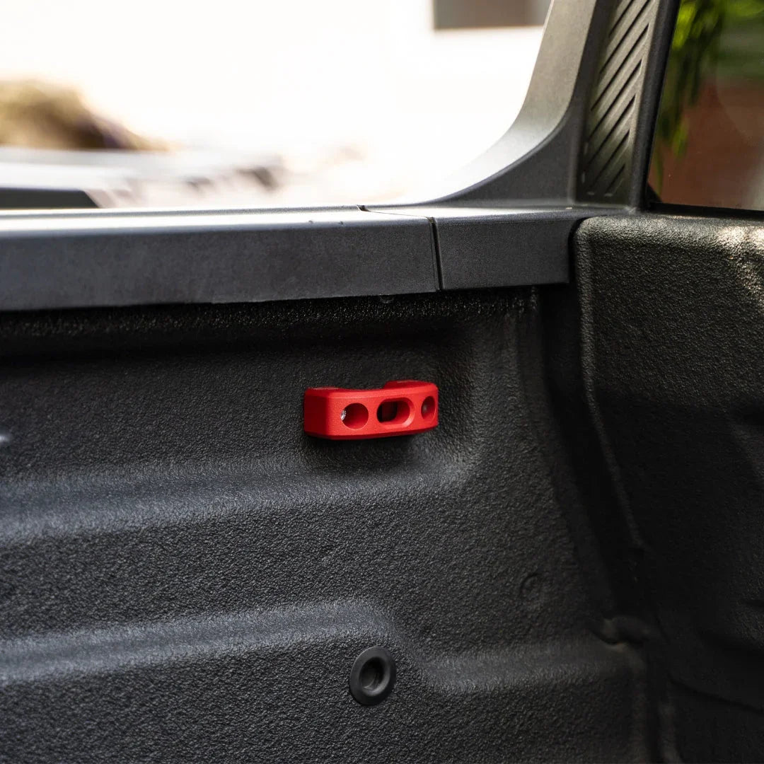 Red powder coated bed tie down installed in Ford Maverick truck bed