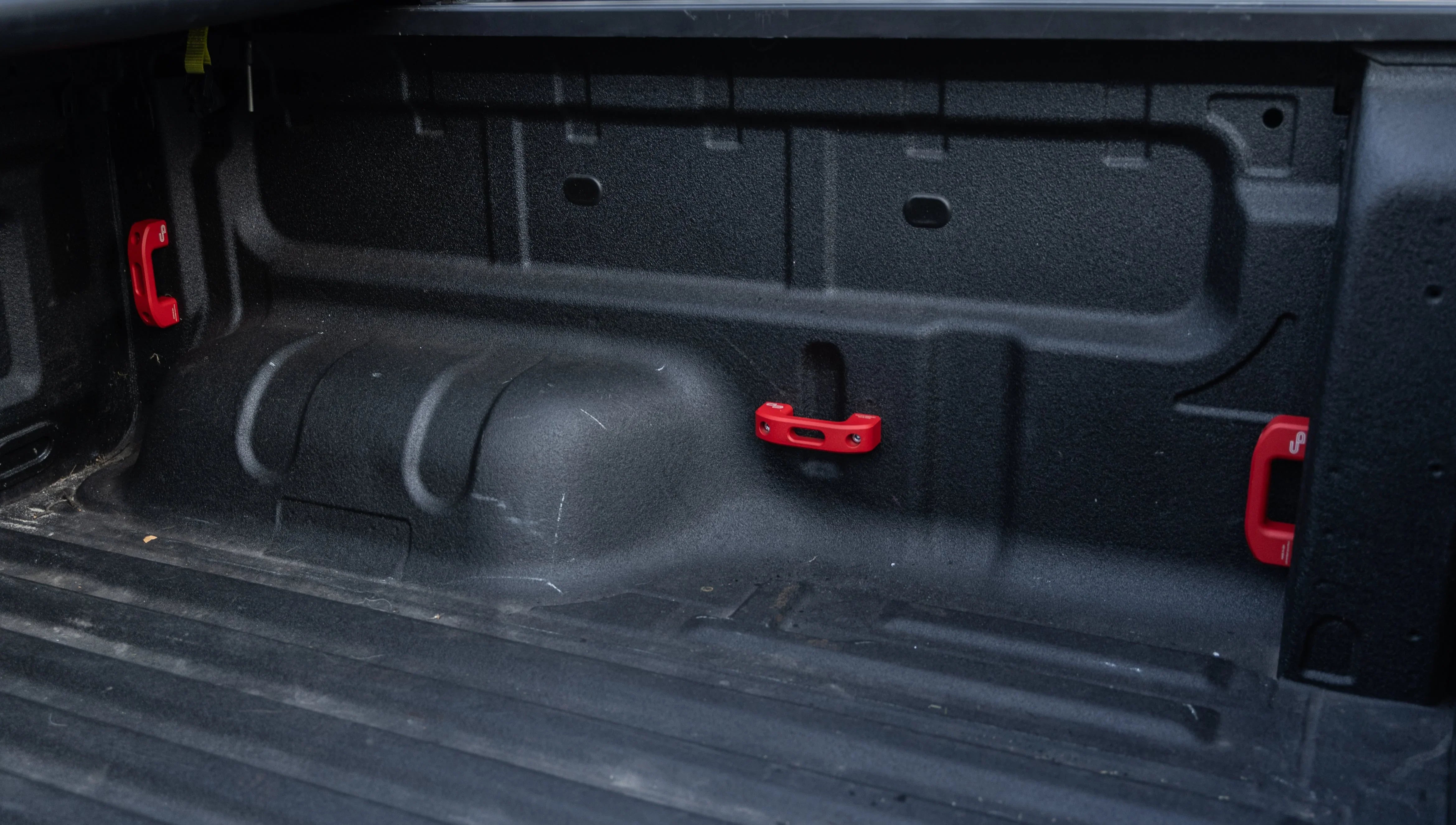 Truck bed interior with red tie-down anchors for overlanding gear