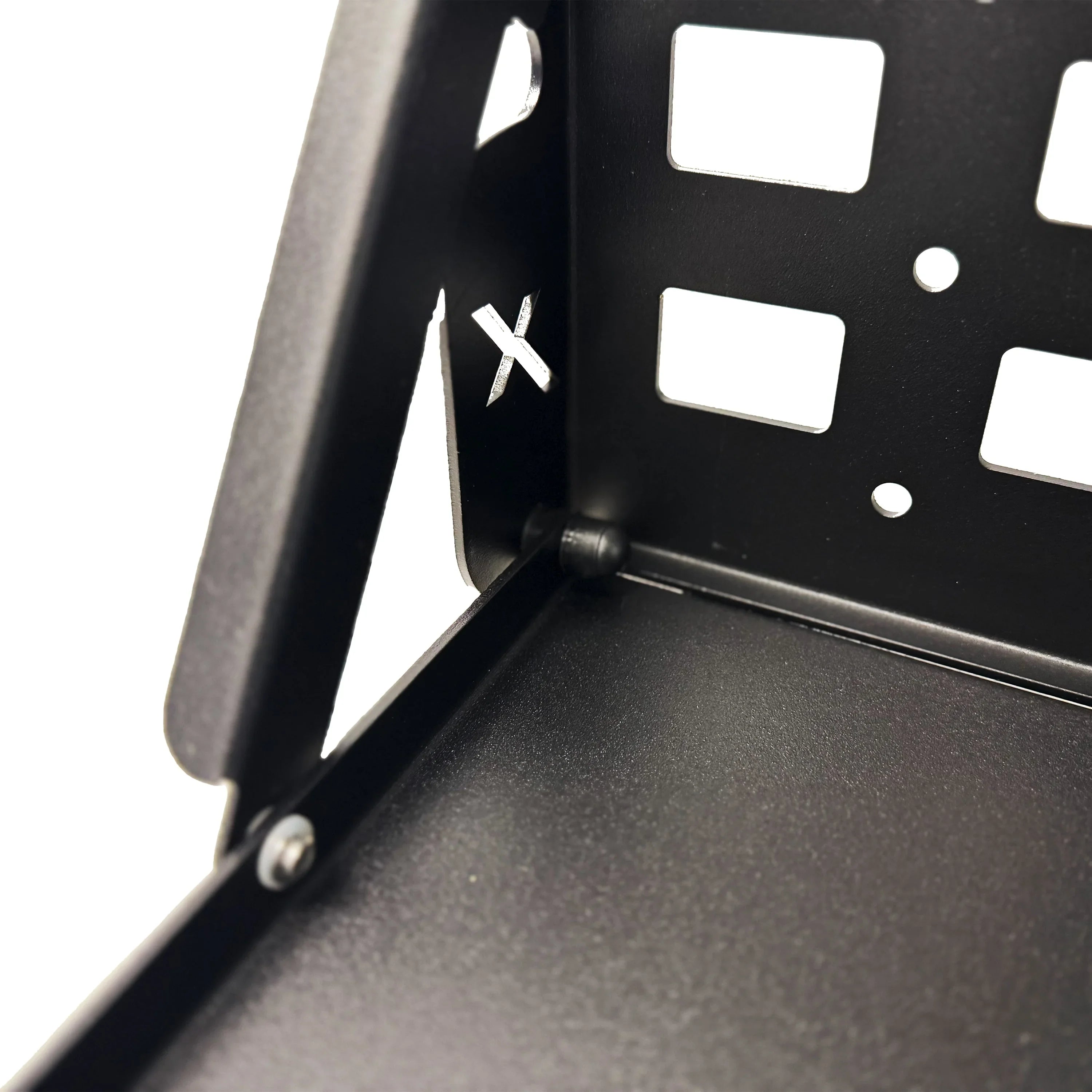 Close-up of black metal mounting bracket with square and X-shaped cutouts for vehicle gear.
