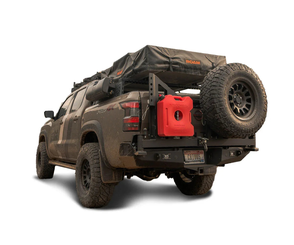 Overland Toyota Tacoma with rooftop tent, spare tire, fuel can, and off-road gear