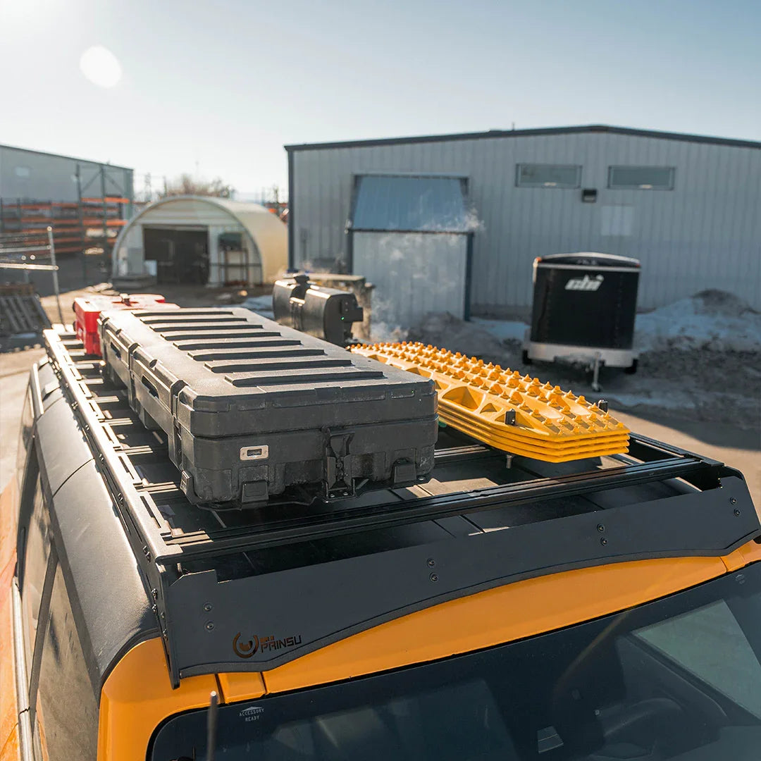 Ford Bronco roof rack loaded with storage cases, traction boards, and fuel cans for overlanding