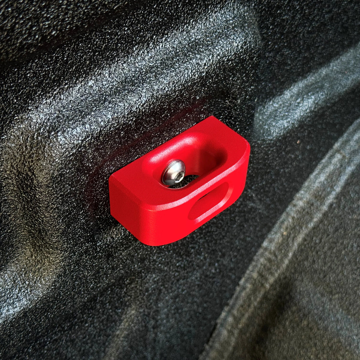 Red aluminum bed tie down anchor installed in a truck bed