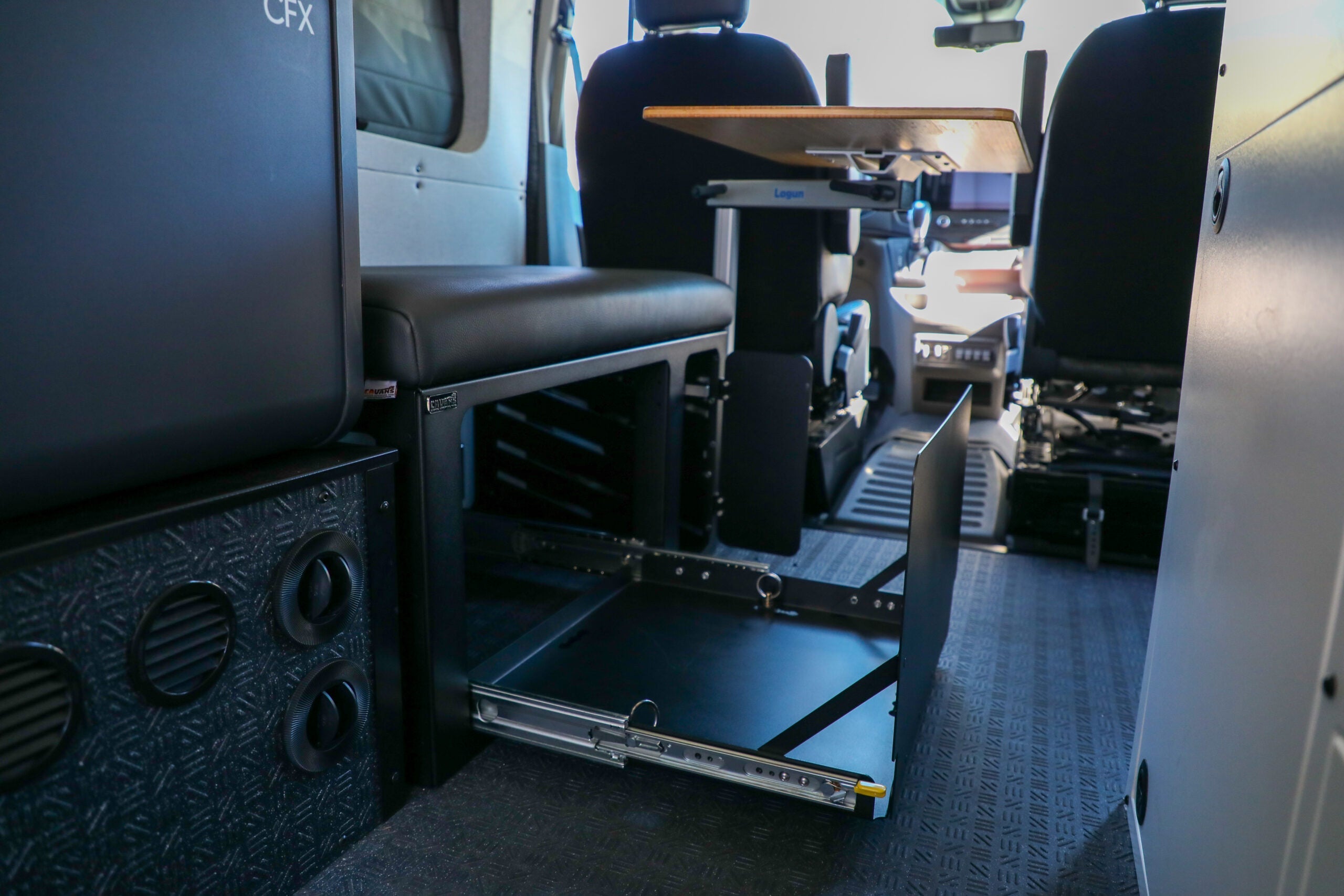 Van interior with bench seat, slide-out storage drawer, and overlanding gear