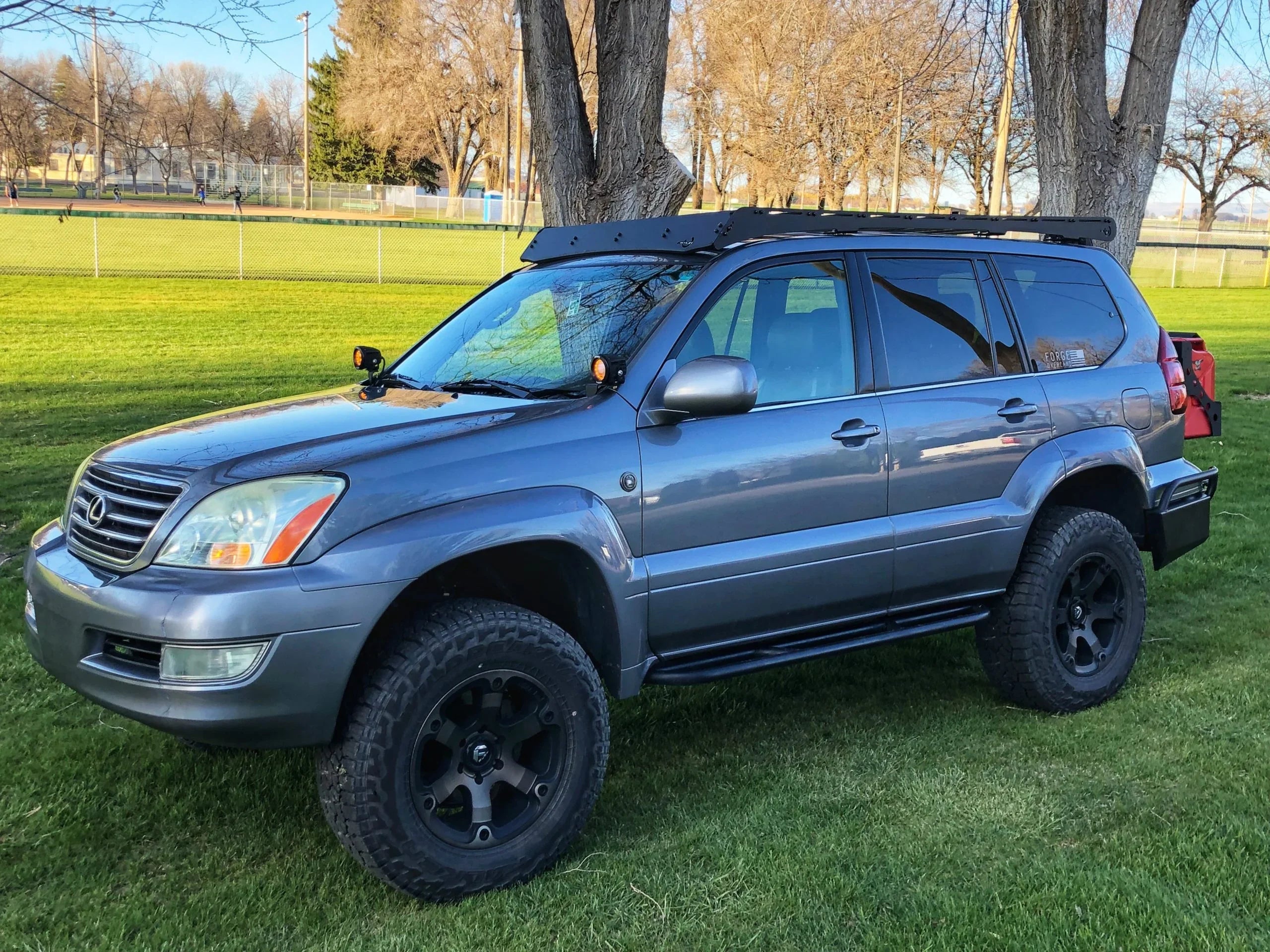 Lifted Lexus GX470 with Prinsu roof rack and off-road accessories in a grassy park.