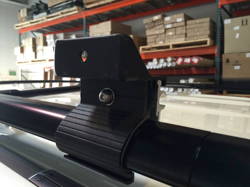 Heavy-duty roof rack clamp bracket mounted on a vehicle crossbar in a warehouse