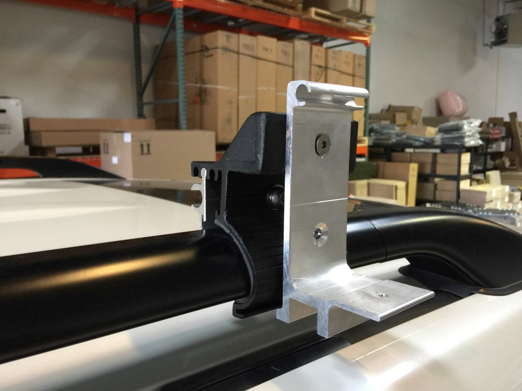 Heavy-duty G clamp with S 2000 mount attached to a vehicle roof rack crossbar in a warehouse