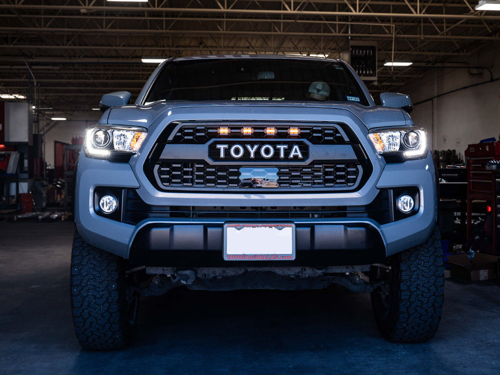 Front view of lifted Toyota Tacoma with aftermarket grille and LED lights in garage