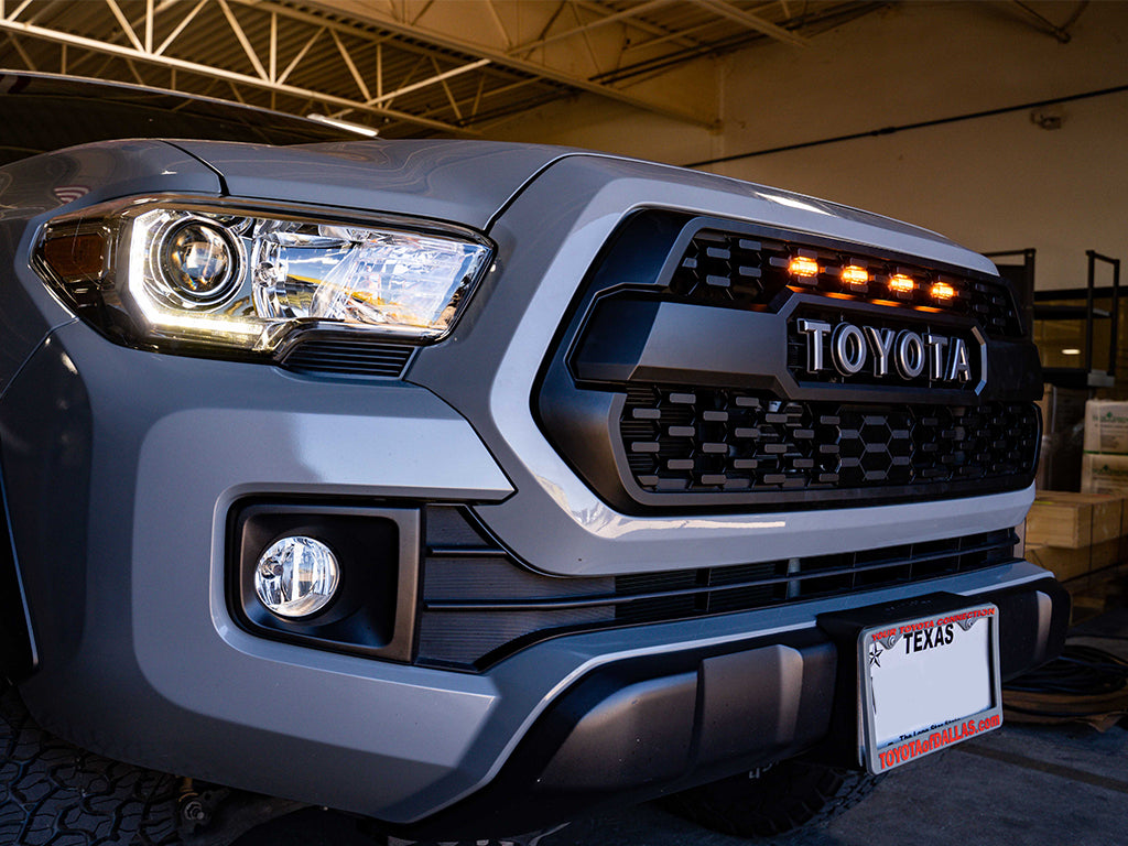 Toyota Tacoma front grille with amber marker lights, headlight and fog light in a garage