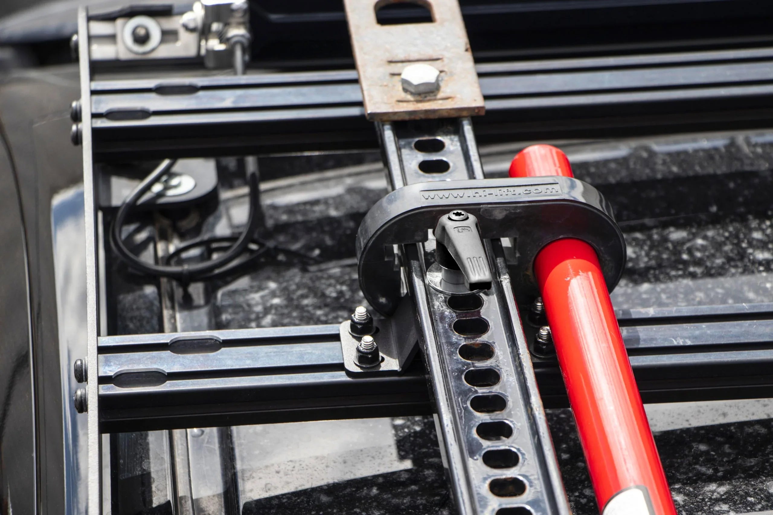 Hi-Lift jack mounted on a vehicle roof rack, overlanding gear close-up