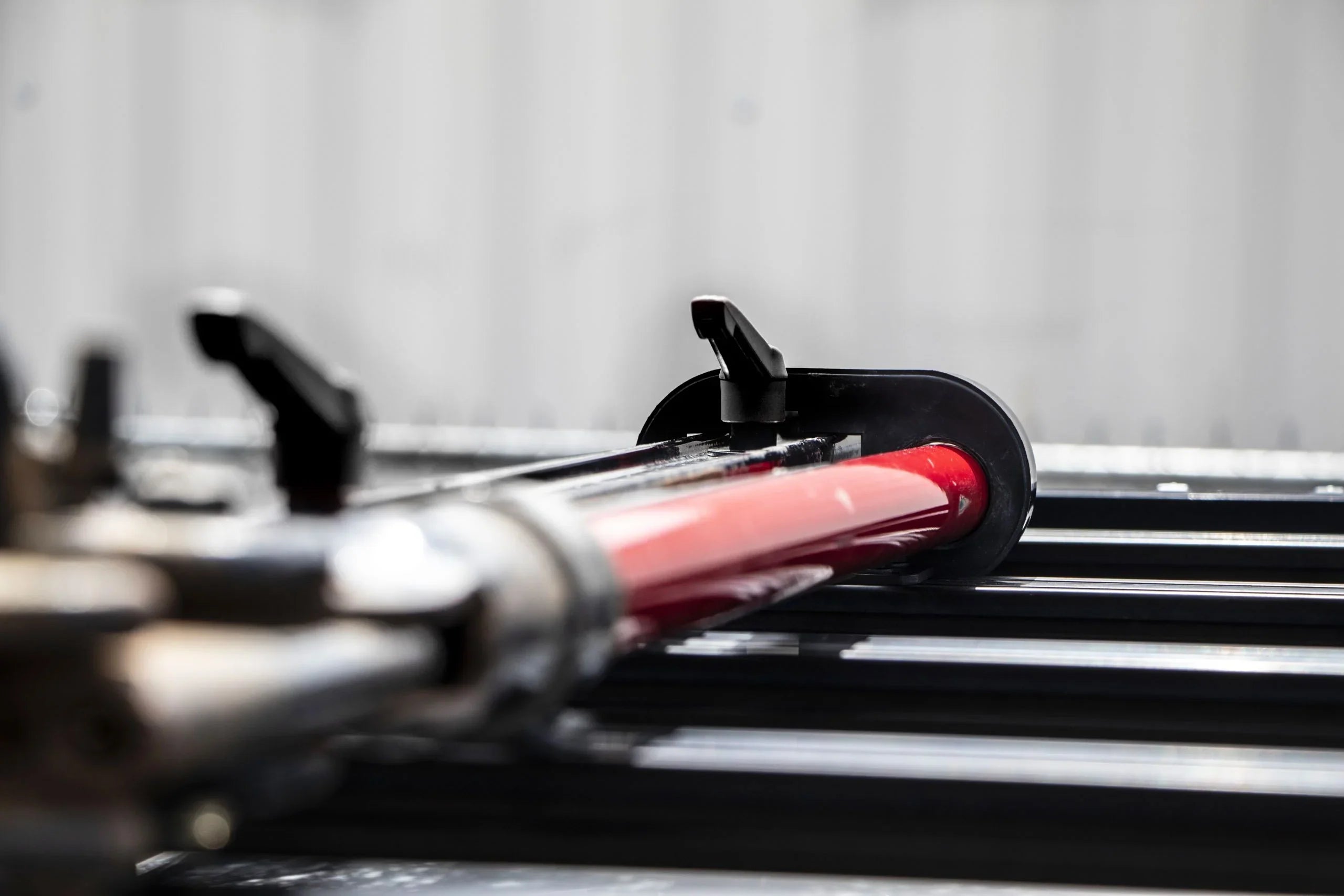Red Hi-Lift jack mounted on a black roof rack for overlanding vehicles